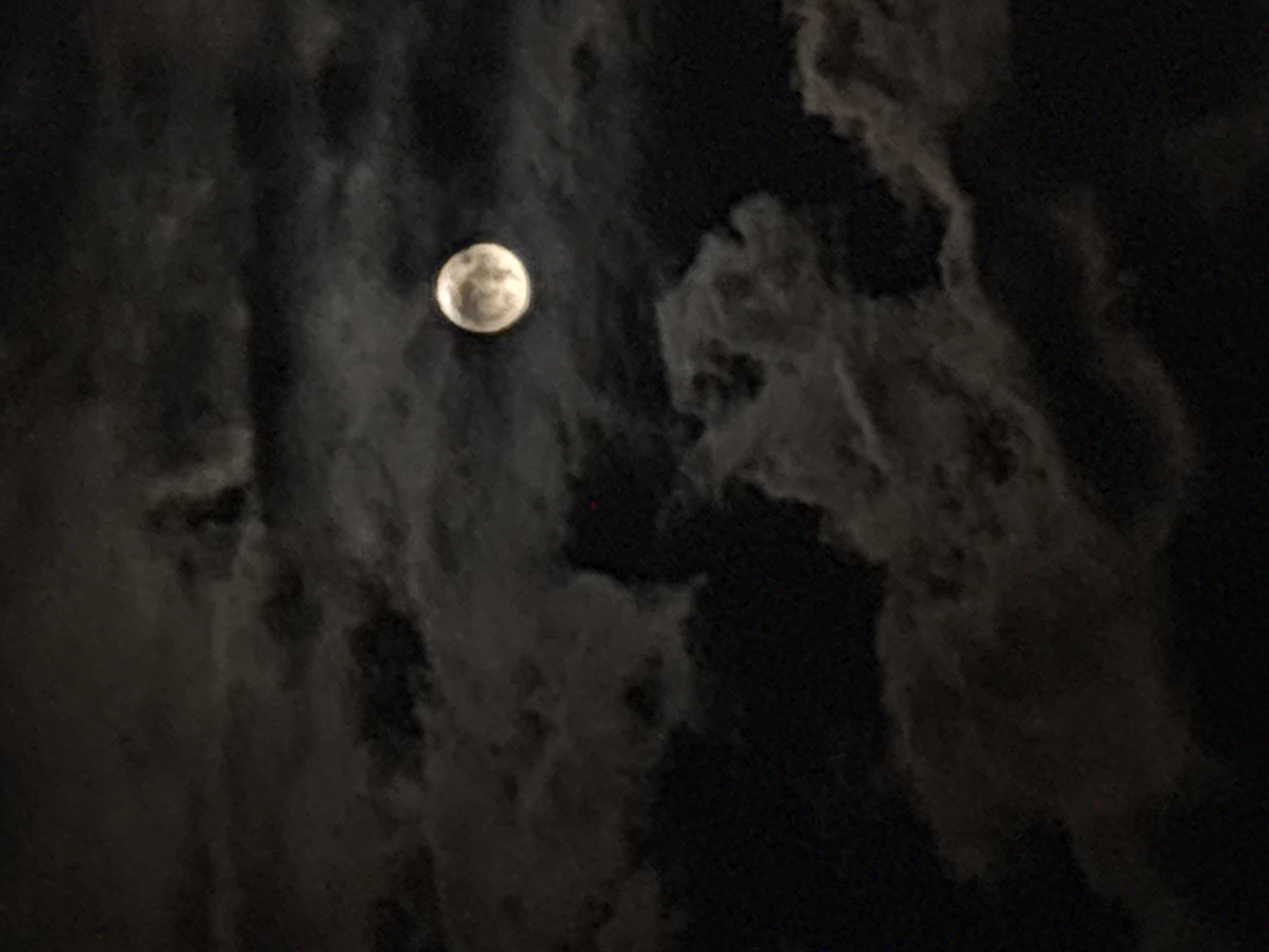 A full moon is visible in the night sky, partially obscured by dark, textured clouds. The image lacks any visible landmarks or context clues to determine its location in Yerevan, Armenia or to confirm the presence of any people or specific objects.