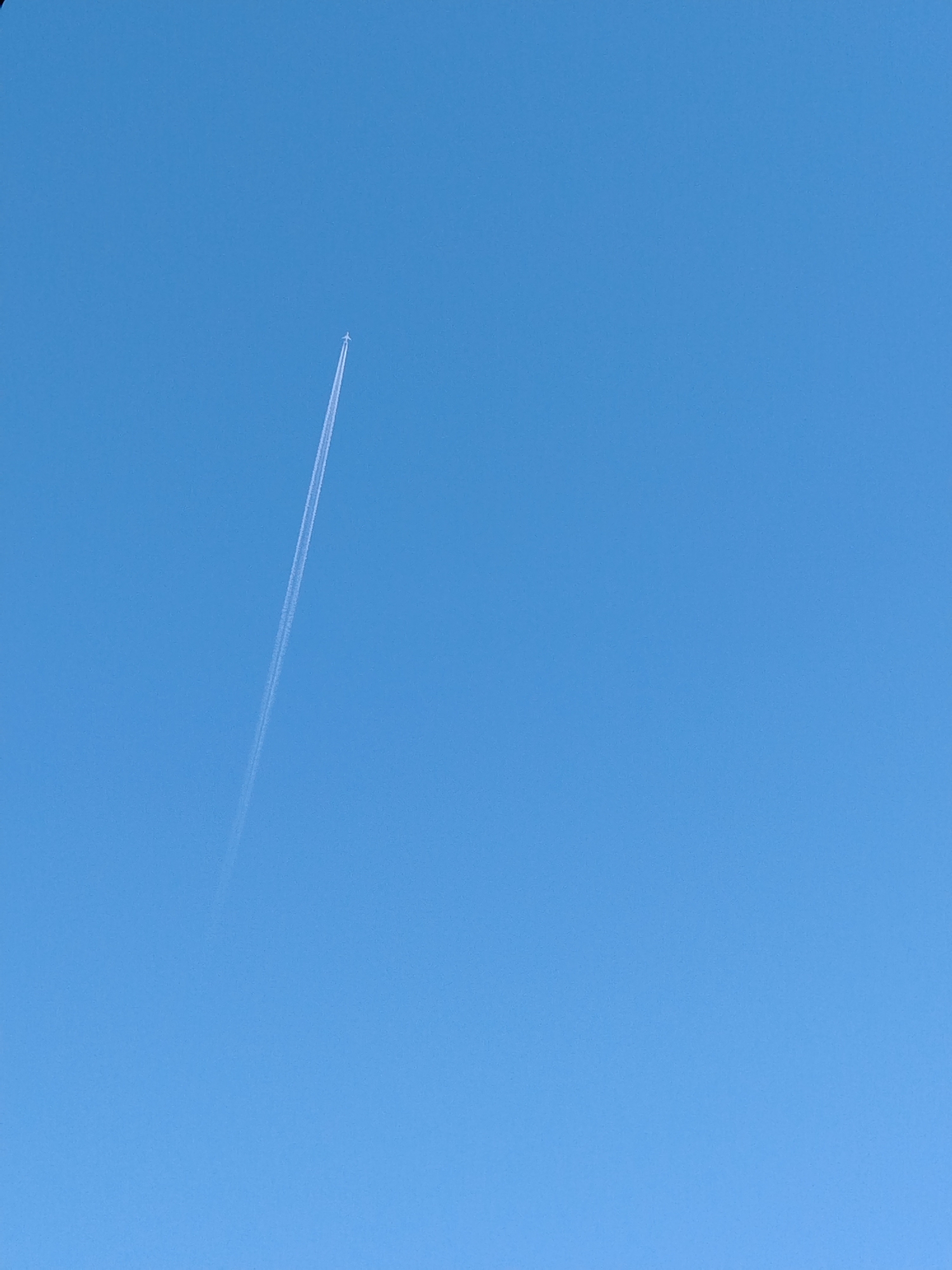 The image shows a light blue sky with a vapor trail from an airplane moving from lower left to upper left. There is no evidence in this image to indicate location in Izhevsk, Russia.