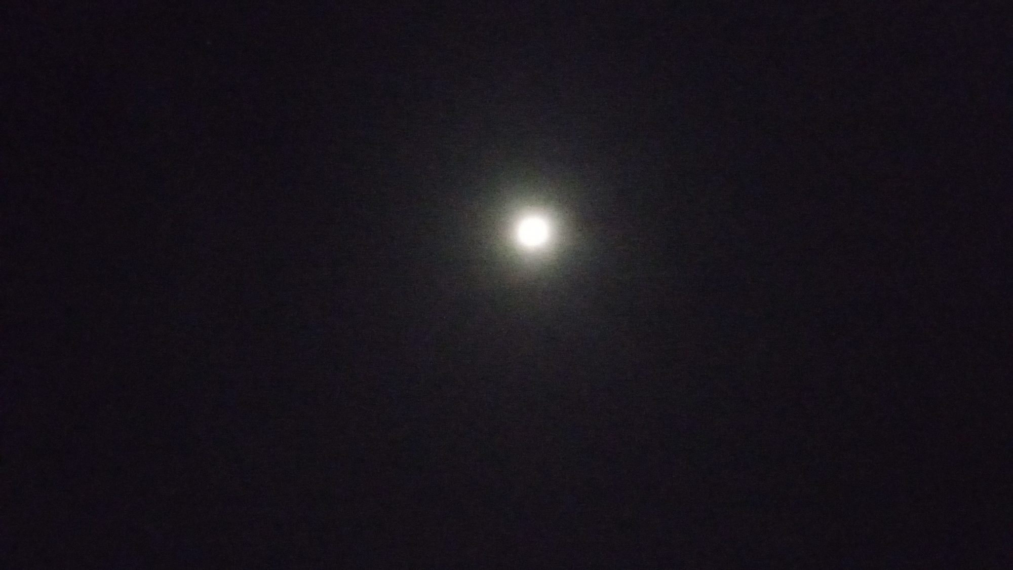 The image shows a brightly illuminated orb, likely the moon, centered in a dark night sky. The background is mostly black, indicating darkness. There is no other context in the image to relate it to the city of Buketteukuh, Indonesia.