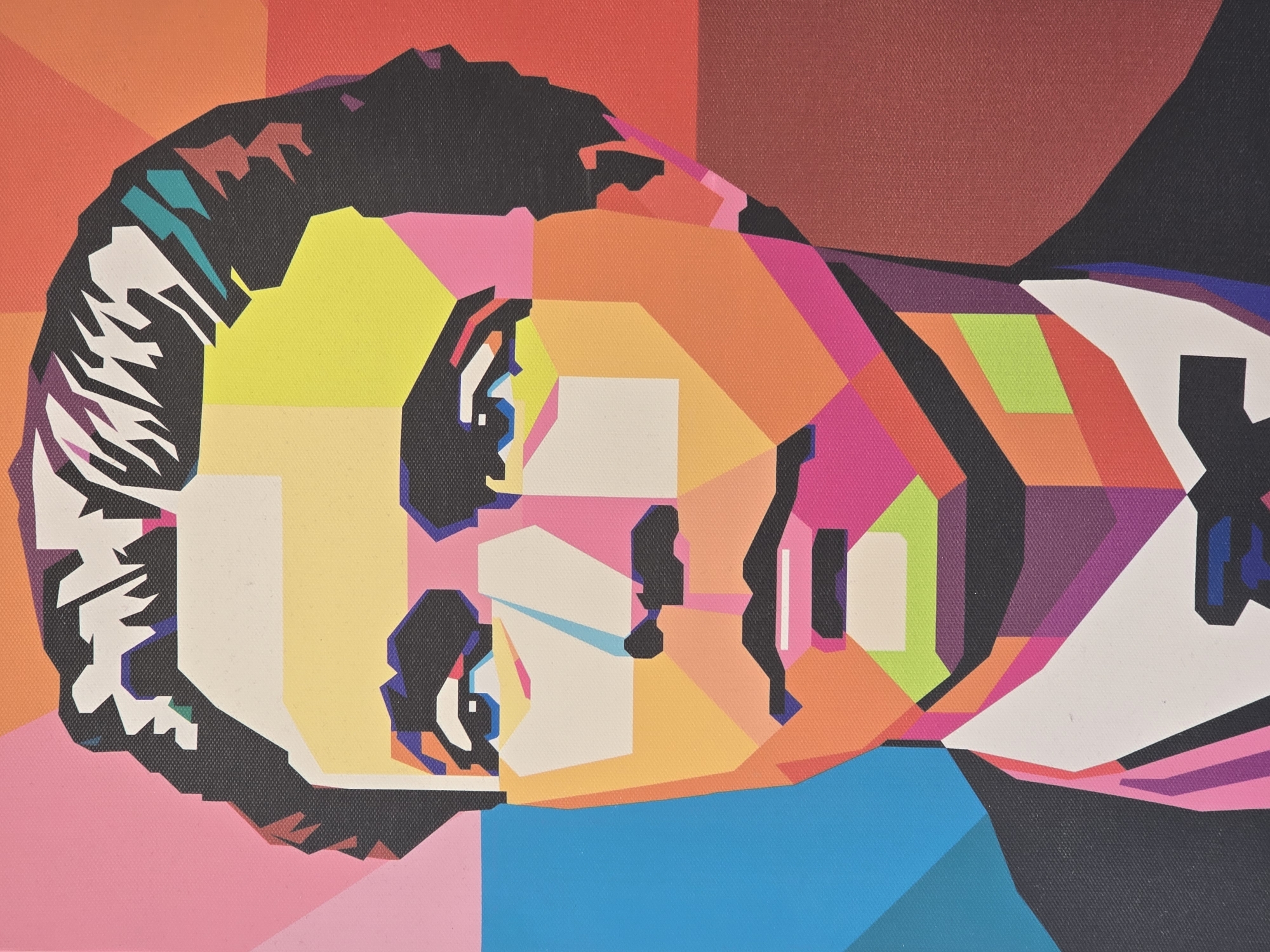 The image displays a vibrant and abstract portrait of a person's head, rendered in a highly stylized geometric pop art fashion. The subject's head is tilted horizontally to the right, filling the majority of the frame.
The face is composed of numerous sharp, angular planes and blocks of contrasting, bright colors. Prominent colors include a bright yellow for the forehead and upper cheek, various shades of orange, pink, and red across the central and lower parts of the face. The hair is depicted in a jagged, dark black shape with highlights of white, teal, and purple. Facial features such as the eyes, nose, and mouth are abstracted into simplified geometric forms, utilizing black outlines, white, and light blue accents.
The background continues the geometric theme, featuring large blocks of color, transitioning from reds and oranges in the upper half to pink in the lower left corner and a solid blue block in the lower right. A subtle canvas or fabric texture is visible across the entire image, indicating it is likely a photograph of a printed artwork or painting. No specific activity or event is taking place beyond the presentation of the portrait itself. There is no visible text in the image.