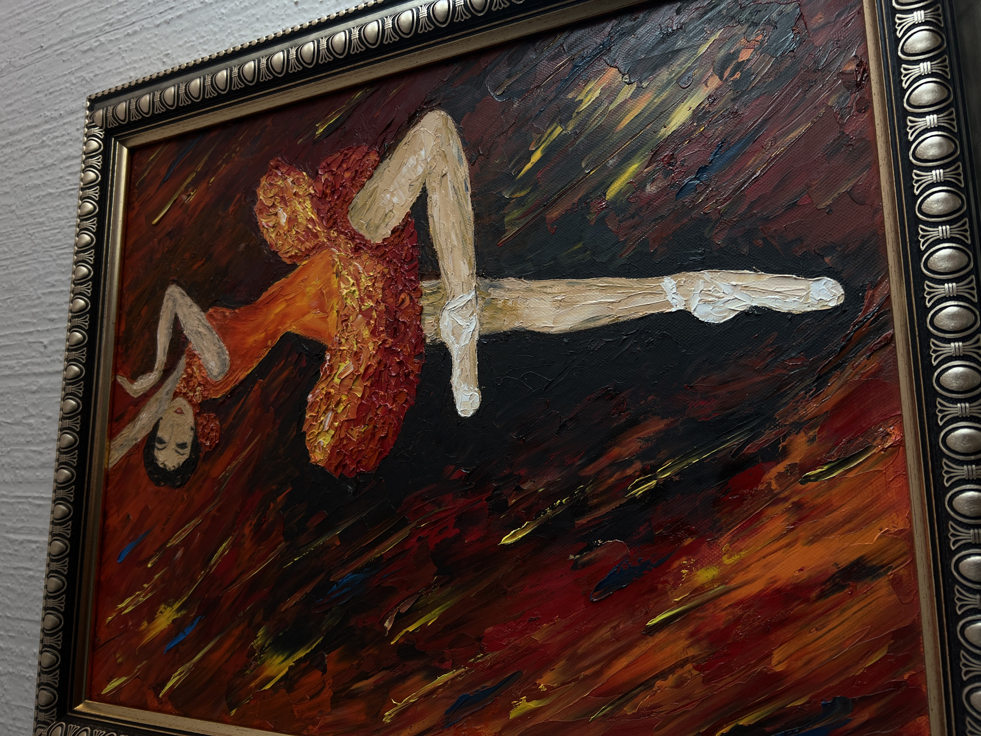 The image shows a framed painting of a ballerina. The painting is rendered in an impressionistic style, with thick brushstrokes and bold colors. The ballerina is depicted mid-leap, wearing an orange tutu. The background is a blend of dark reds, oranges, and yellows. The frame is ornate and features a metallic finish. The location, Mexico City, is not apparent from the image content.