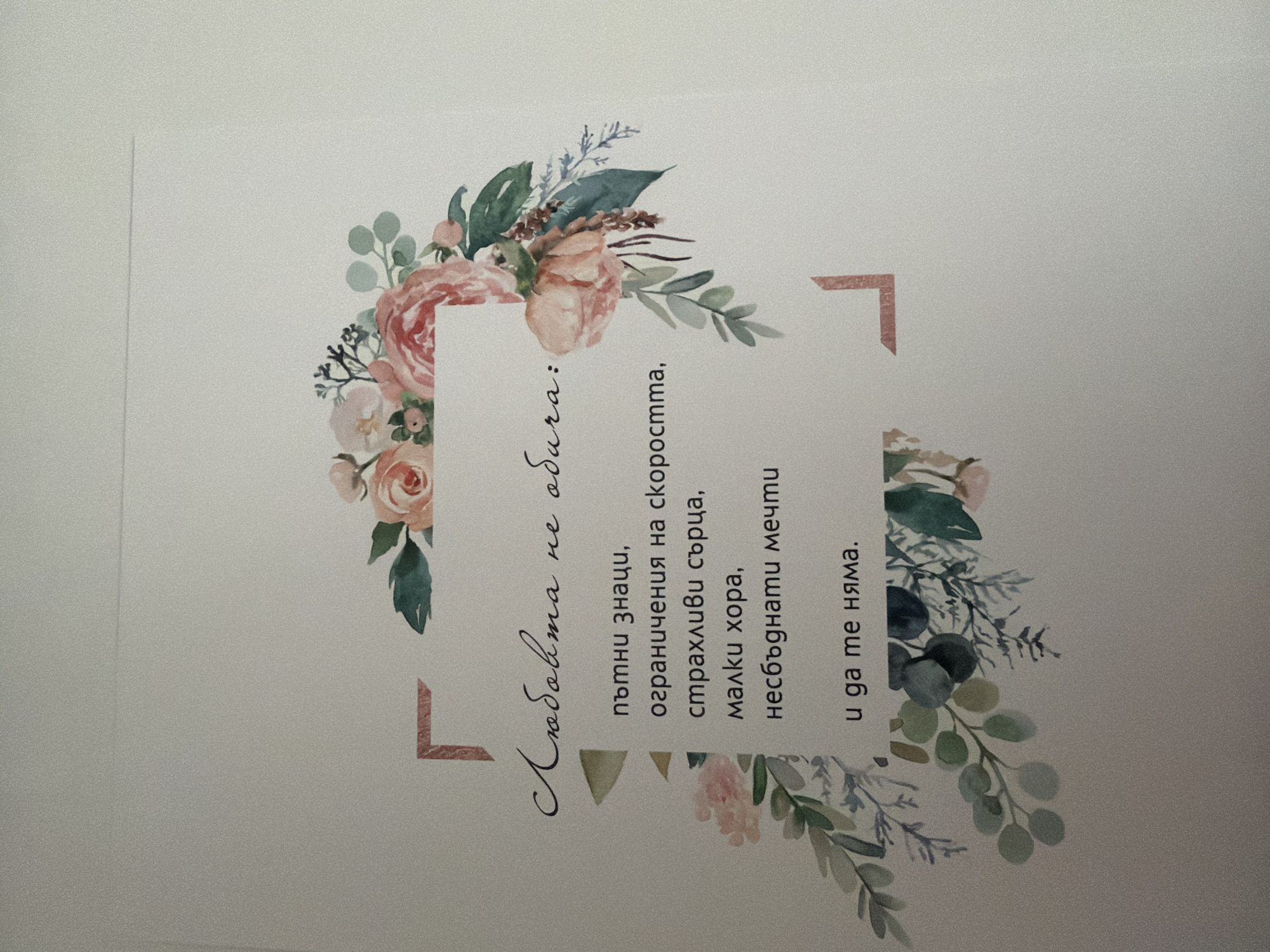 The image displays a piece of paper with floral watercolor illustrations and text in Bulgarian. The text reads: "Любовта не обича: пъпни знаци, ограничения на скоростта, страхливи сърца, малки хора, несбъднати мечти и да те няма." This translates to: "Love does not love: signs of immaturity, speed limits, fearful hearts, small people, unfulfilled dreams, and for you not to be there." The floral design features pink and peach roses and green leaves arranged in a decorative frame around the text. The background is a light, textured surface. The image does not contain any information about the city of Pazardzhik, Bulgaria, or any people or actions.