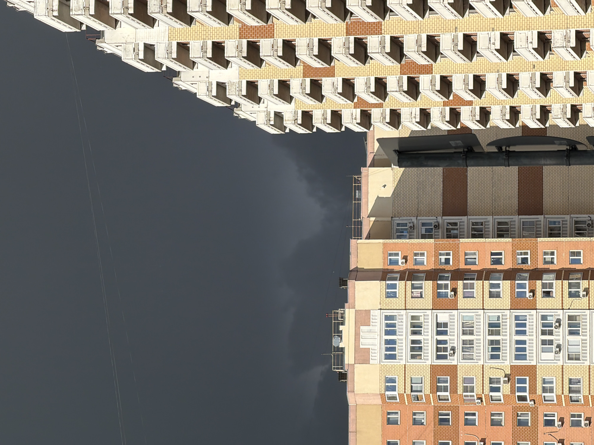 An aerial shot shows a high-rise building complex in Khimki, Russia, under an overcast sky. The buildings feature a mix of brick and painted facades, with rows of windows and protruding balconies. Rooftop fixtures and utility lines are visible.