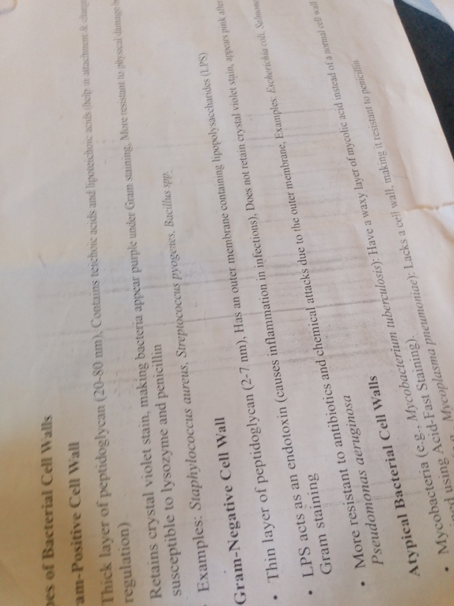 The image shows a close-up of a document with text printed on it. The text is oriented diagonally, making it slightly difficult to read. The document appears to be a page from a textbook or study material, discussing different types of bacterial cell walls.
The subjects are purely textual, as there are no images of people, objects, or scenes. The setting is implied to be an indoor environment where documents are typically found, such as a study desk or a classroom.
The activity taking place is the presentation of information on bacterial cell wall types, including Gram-Positive, Gram-Negative, and Atypical. The text details the characteristics of each type, their resistance to stains and antibiotics, and provides examples of bacteria belonging to each category.
Notable details include the specific scientific terms used, such as "peptidoglycan," "lipoteichoic acids," "lipopolysaccharides (LPS)," "endotoxin," and "mycolic acid." The examples of bacteria mentioned are "Staphylococcus aureus," "Streptococcus pyogenes," "Bacillus spp.," "Escherichia coli," "Salmonella," "Pseudomonas aeruginosa," "Mycobacterium tuberculosis," and "Mycoplasma pneumoniae." The text also refers to "Gram staining" and "Acid-Fast Staining." There are no cues for time of day, weather, or specific location within Jalingo, Nigeria, beyond the context provided in the prompt.
The visible text is the entirety of the content in the image, and it is about microbiology, specifically bacterial cell walls.