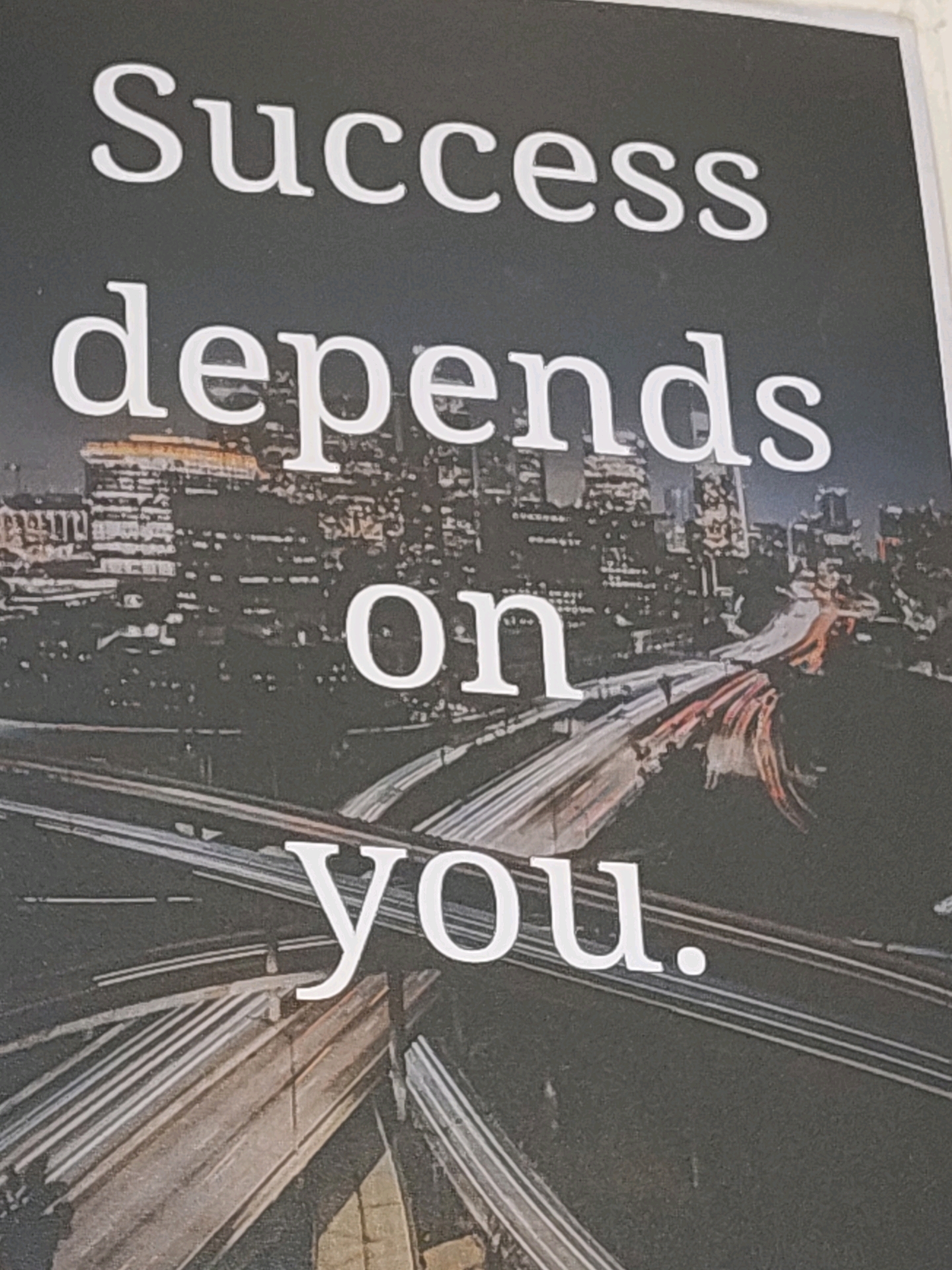 The image displays text overlaid on a nighttime cityscape with a complex network of illuminated highways. The text reads "Success depends on you." The background shows a blurred panorama of city lights, buildings, and the intersecting roads of a highway interchange. The text is white and appears to be printed or digitally overlaid onto the image. There are no people visible in the image. The scene depicts a motivational message against an urban backdrop. This image is not related to Tathawade, India.