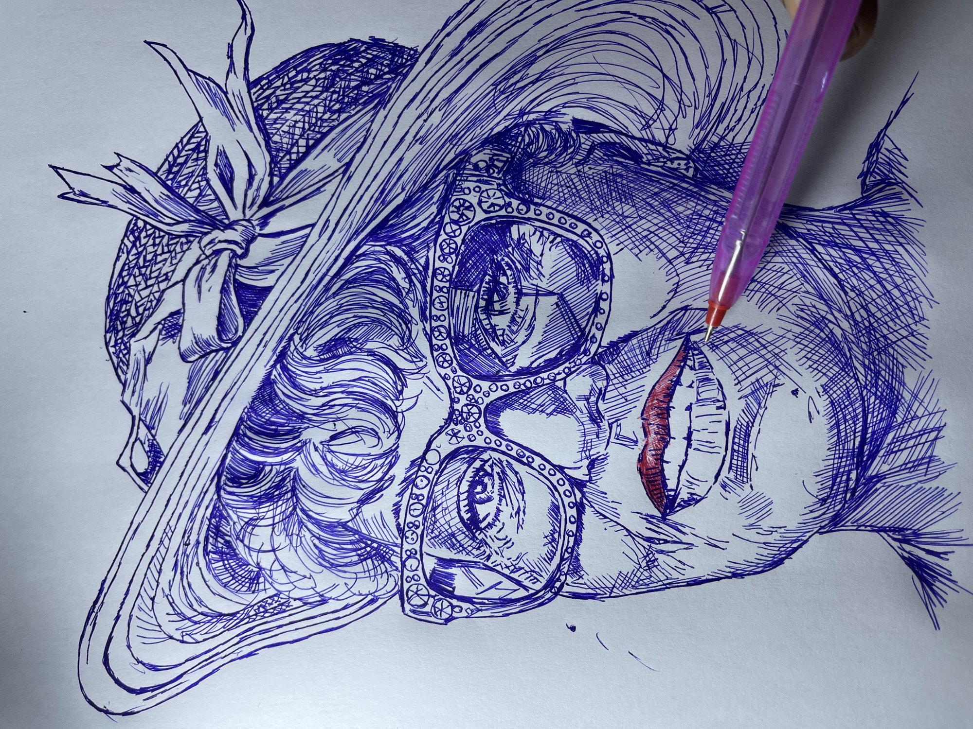 The image is a close-up pen and ink drawing of a woman wearing a wide-brimmed hat and large, ornate glasses. She has red lipstick on and her mouth is slightly open, revealing her teeth. The drawing is done in blue ink with red highlights on the lips. A pink pen is visible in the lower right corner, being held by an unseen hand, suggesting the drawing is in progress. The background is plain white paper. There is no indication of a specific location within the city of Jos, Nigeria, or any environmental details that would suggest such a setting. The focus is entirely on the portrait.