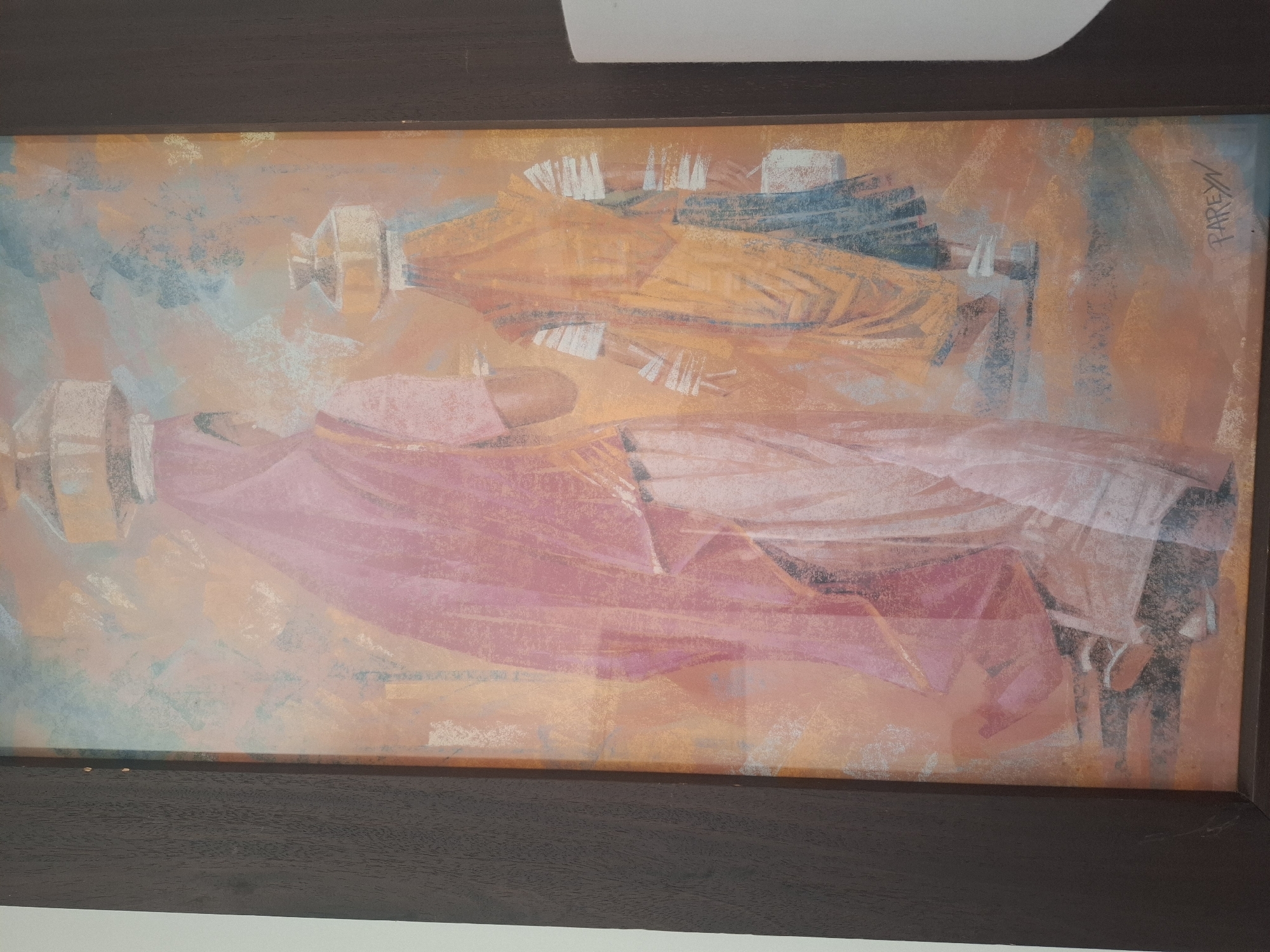The image is a framed painting depicting two women walking, viewed from behind. The woman in the foreground wears a flowing pink garment and a headscarf, carrying a large pot on her head. The woman behind her wears an orange garment and also carries a pot on her head. Both figures are stylized, with soft, blended colors. The background is abstract, with washes of orange, blue, and light pink, suggesting an outdoor environment. A signature, "PAREYN", is visible in the lower right corner. The painting is hung on a wall in a room. The location is identified as the city of Montreuil, France.