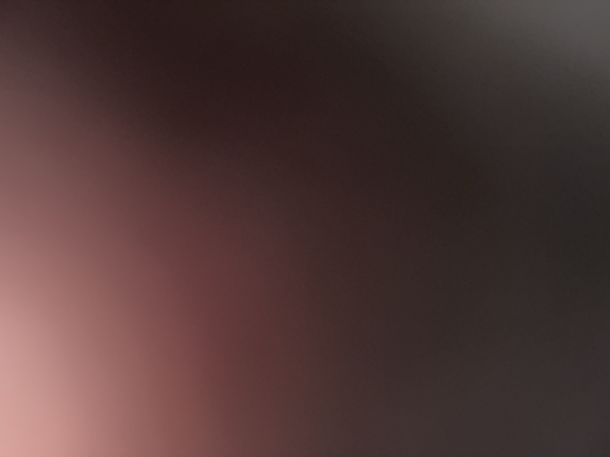 The image is a blurred, abstract photograph with a gradient of colors ranging from a soft pinkish hue in the top left corner to a deep brown in the bottom right. There are no discernible objects, people, or actions visible in the image. The background appears to be a smooth, uniform surface, possibly a wall or fabric, illuminated by a light source that creates the color gradient. The overall impression is one of soft, diffused light and color. The image does not contain any specific details that would allow for identification of its location in Belgrade, Serbia, or any other urban environment.