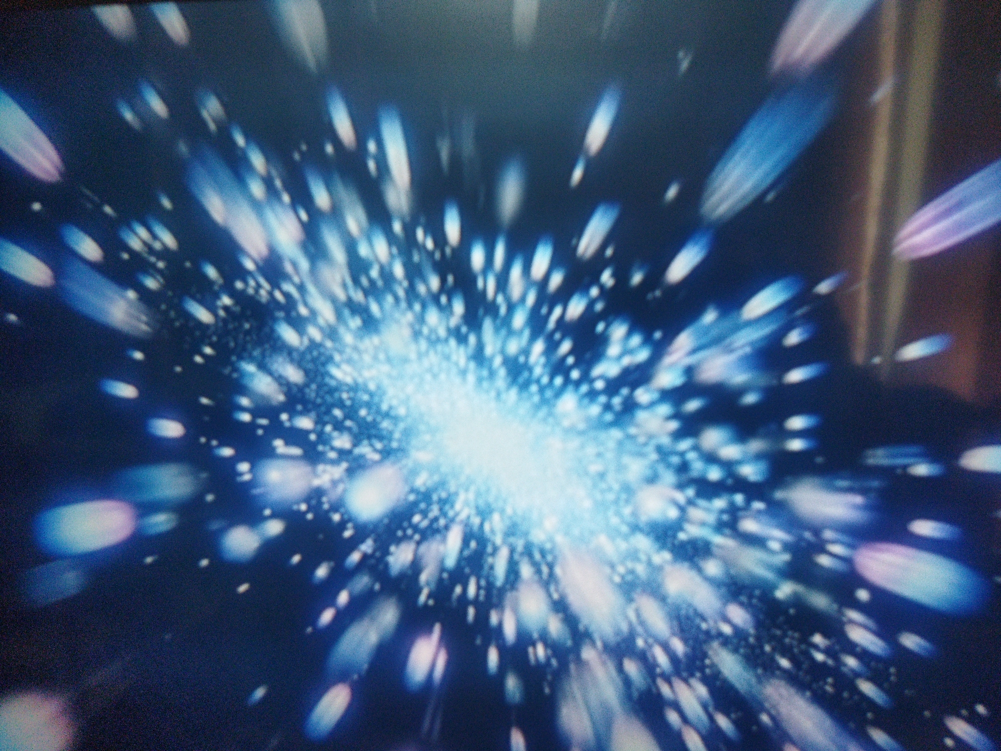 The image shows an abstract pattern of radiating blue and white lights against a dark background. There is a concentrated burst of light in the center, from which streaks and dots of light emanate outward. The light appears blurred, suggesting motion or an out-of-focus effect. There are no discernible people, subjects, objects, actions, interactions, or specific environmental details present in the image that would allow it to be located in Kramatorsk, Ukraine.