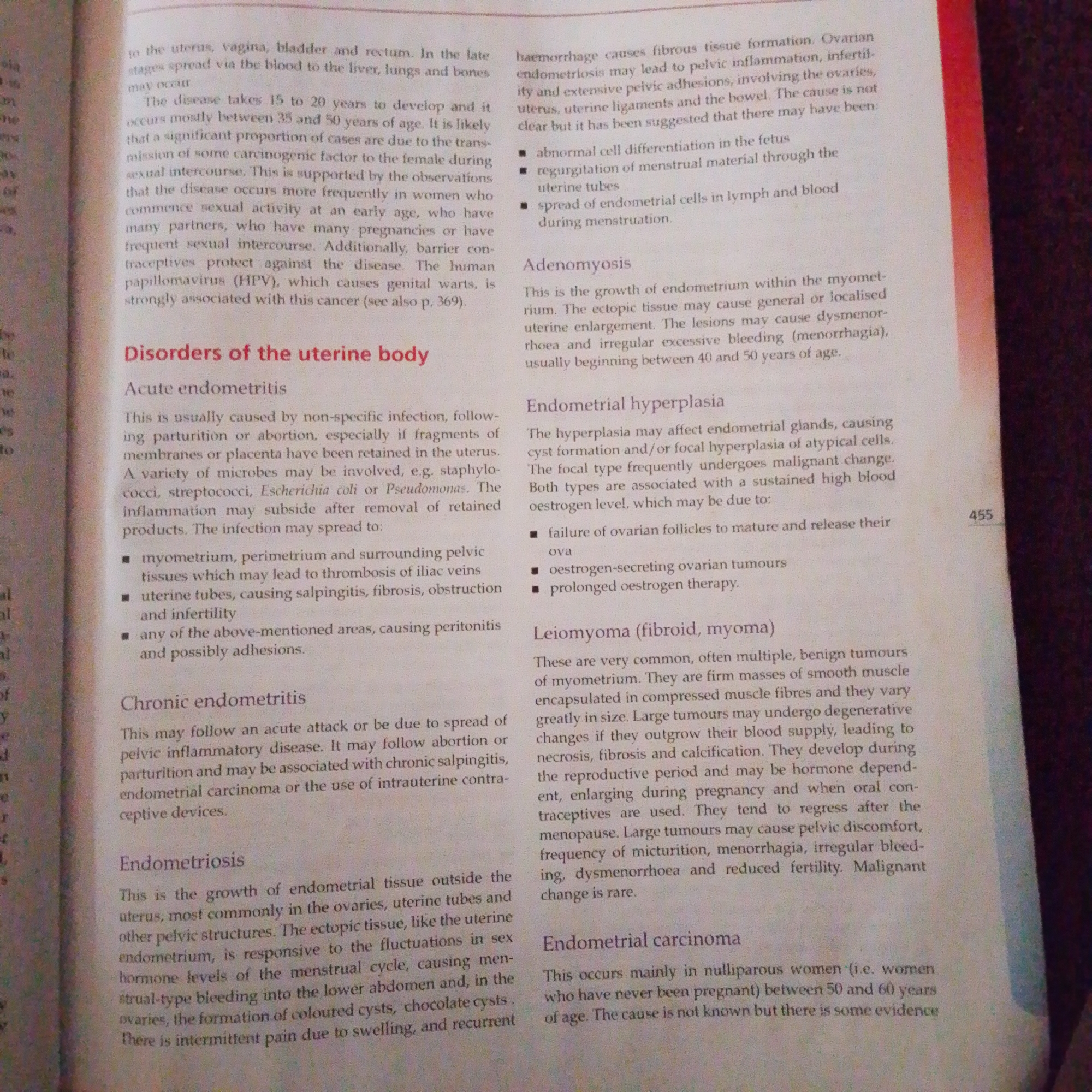The image is a close-up, slightly angled shot of a page from a medical textbook. The text discusses various disorders of the uterine body, including acute endometritis, chronic endometritis, endometriosis, adenomyosis, endometrial hyperplasia, leiomyoma (fibroid, myoma), and endometrial carcinoma. The page is primarily text-based, with a few bullet points used for listing symptoms or causes. The background is a slightly textured off-white, suggesting paper. The overall presentation is that of an educational document. There are no elements in the image that would indicate a location in Jalingo, Nigeria, or any forensic details.