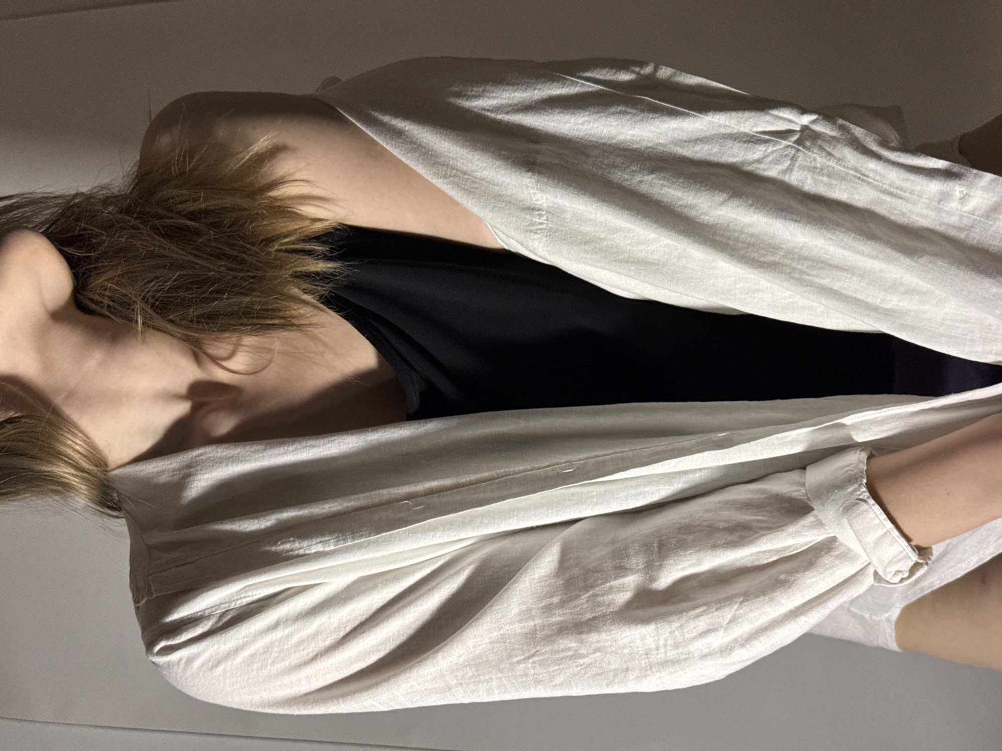 A woman with blonde hair is lying down, wearing a black top and a white unbuttoned shirt. The background is plain and light. The image provides no information about the location being in Chaikovsky, Russia.