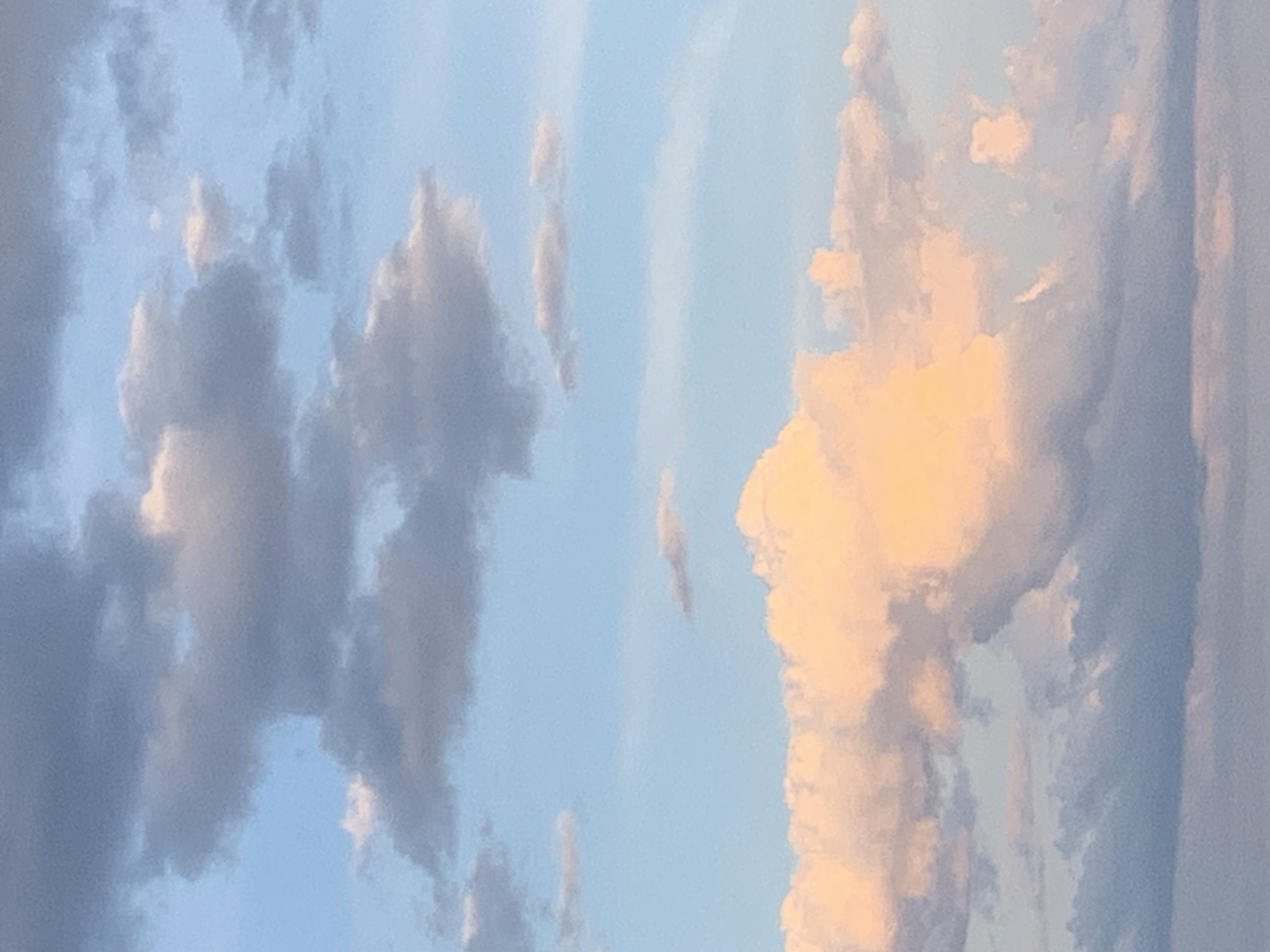 This media file depicts a close-up view of the sky filled with clouds. The clouds are varied in appearance, with some being dark and shadowed, while others are illuminated with a warm, golden light, suggesting a sunset or sunrise. The sky is a clear blue in the background, providing a contrast to the textured clouds. There are no people or objects visible in the frame, only the atmospheric elements of the sky. The image captures the natural beauty of cloud formations. There is no visible text in the image. The lighting suggests it is either dawn or dusk.