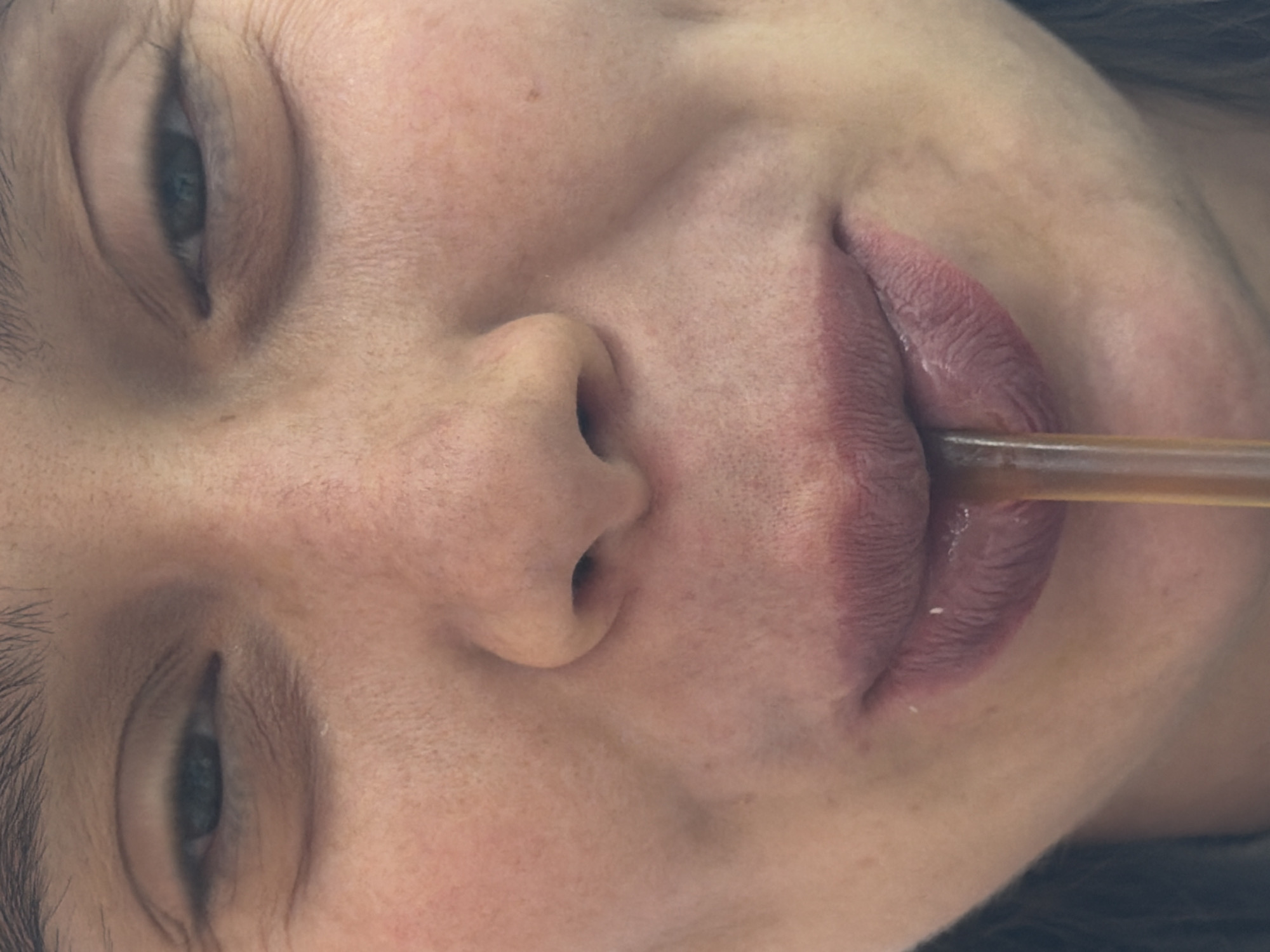 A close-up of a person's face is displayed. The person is holding a brown straw between their lips. The person's eyes are partially closed. The location, Niles, United States of America, is not represented in this image.