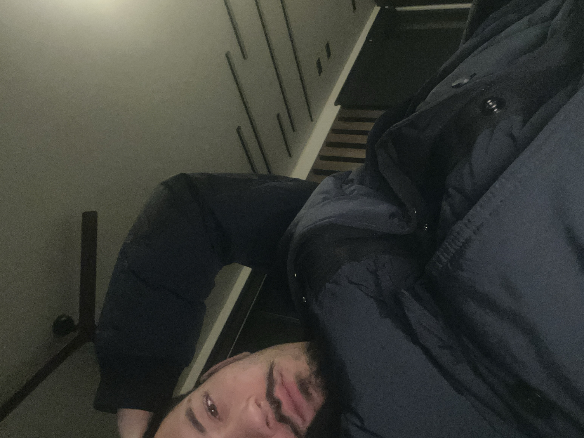 A selfie taken inside a stairwell. A person wearing a dark jacket is positioned in the foreground. The background shows a wall with vertical indentations and wooden stairs. The exact location within Plovdiv, Bulgaria, cannot be determined from the provided image.