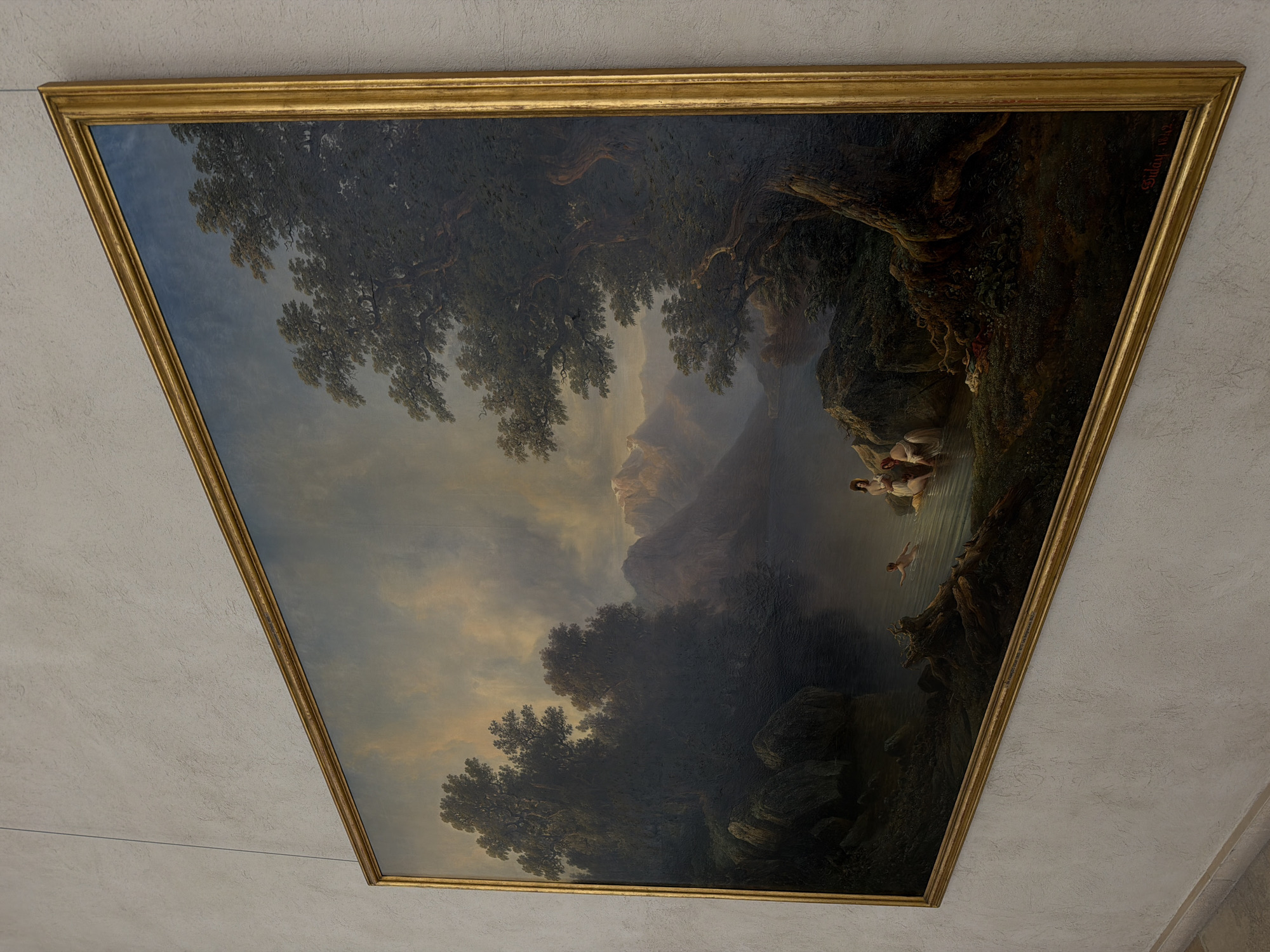 The image shows a large, ornate, gold-framed oil painting of a landscape scene. The painting depicts a body of water, possibly a lake or river, with mountains in the background. Lush, dark green trees frame the scene on the left and right sides, with one large tree dominating the right foreground. The sky is cloudy with dramatic lighting, suggesting a twilight or stormy atmosphere. In the foreground, on the edge of the water, several figures are depicted. One figure, appearing to be a child, is swimming in the water. Two other figures, appearing to be women, are partially in the water and interacting with each other. There are rocks and vegetation along the shoreline. A signature and date are visible in the lower right corner of the painting, reading "Suday 1842".
This painting is located in the Kunstmuseum Basel in Basel, Switzerland.