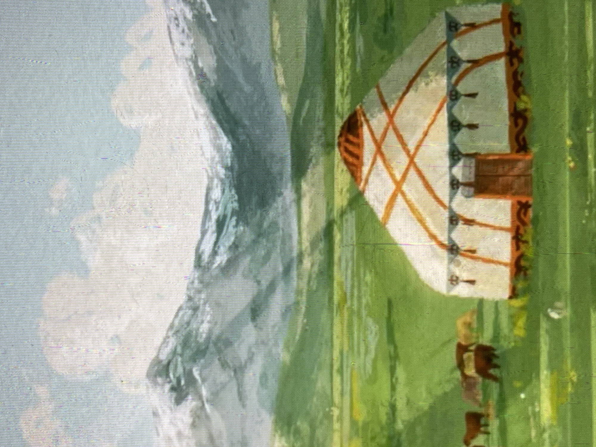 The image depicts a pastoral scene with a yurt as the central element. The yurt is conical with a wooden door and decorative elements. It is situated in a vast, green meadow under a bright sky with clouds. In the background, rolling hills transition to snow-capped mountains. Several horses are scattered across the meadow, grazing. The overall impression is one of a serene, natural landscape. While the scene evokes a sense of rural Kyrgyzstan, the image does not provide specific visual cues to pinpoint a location within the city of Bishkek.