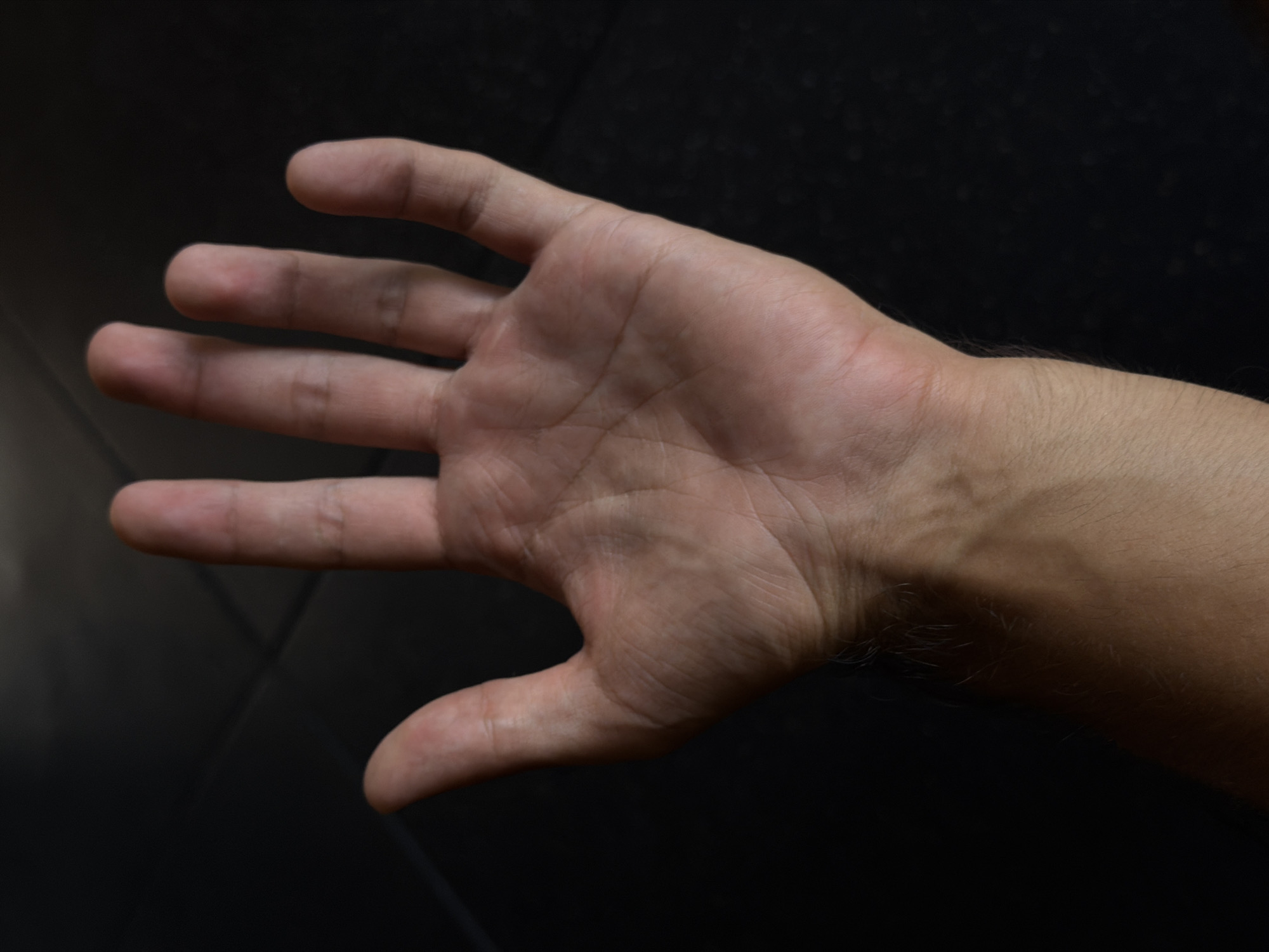 A medium-shot image shows an open left hand, palm up, against a dark background. The hand extends from the wrist, with visible veins and hair on the forearm. The fingers are spread, and the palm exhibits skin creases and texture. The background appears to be a dark, non-reflective surface. The image appears to have been taken indoors with relatively soft lighting. The location of North Kuta, Indonesia is not apparent from this image.