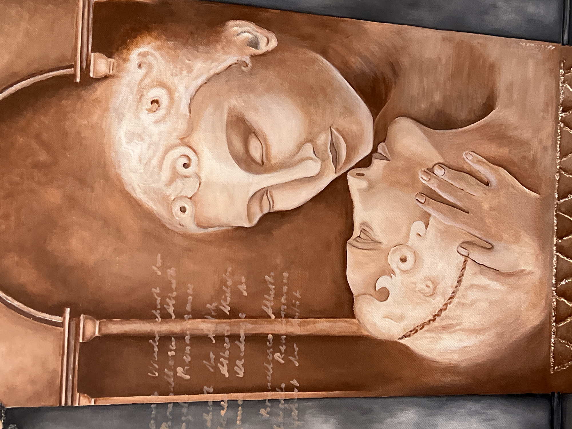 This is a vertical, close-up painting of two monochromatic figures, rendered in warm, earthy tones, seemingly carved from stone. The background is a muted brown, with hints of architectural elements like columns and an archway suggesting an interior setting.
The upper figure is seen from the shoulders up, with its head tilted downwards towards the lower figure. Its eyes are closed, and its expression is serene. Intricate, coiled decorations adorn the hairline and forehead.
The lower figure is also seen from the shoulders up, its head tilted back and resting on what appears to be a hand. Its eyes are also closed, and its lips are slightly parted, as if in anticipation or receiving a kiss. A thin, rope-like chain is visible around the neck. The hand of the upper figure gently touches the chin and cheek of the lower figure.
To the left of the figures, there is text written in a cursive script, appearing to be ancient writing or a symbolic inscription, but it is illegible. The bottom of the painting features a decorative border with a repeating geometric pattern, accented with gold.
This artwork is located within the Norviliškės Castle in Norviliškės, Lithuania, a historic building that serves as a cultural and event venue. The painting's style and subject matter suggest a romantic or historical theme, fitting for the setting.