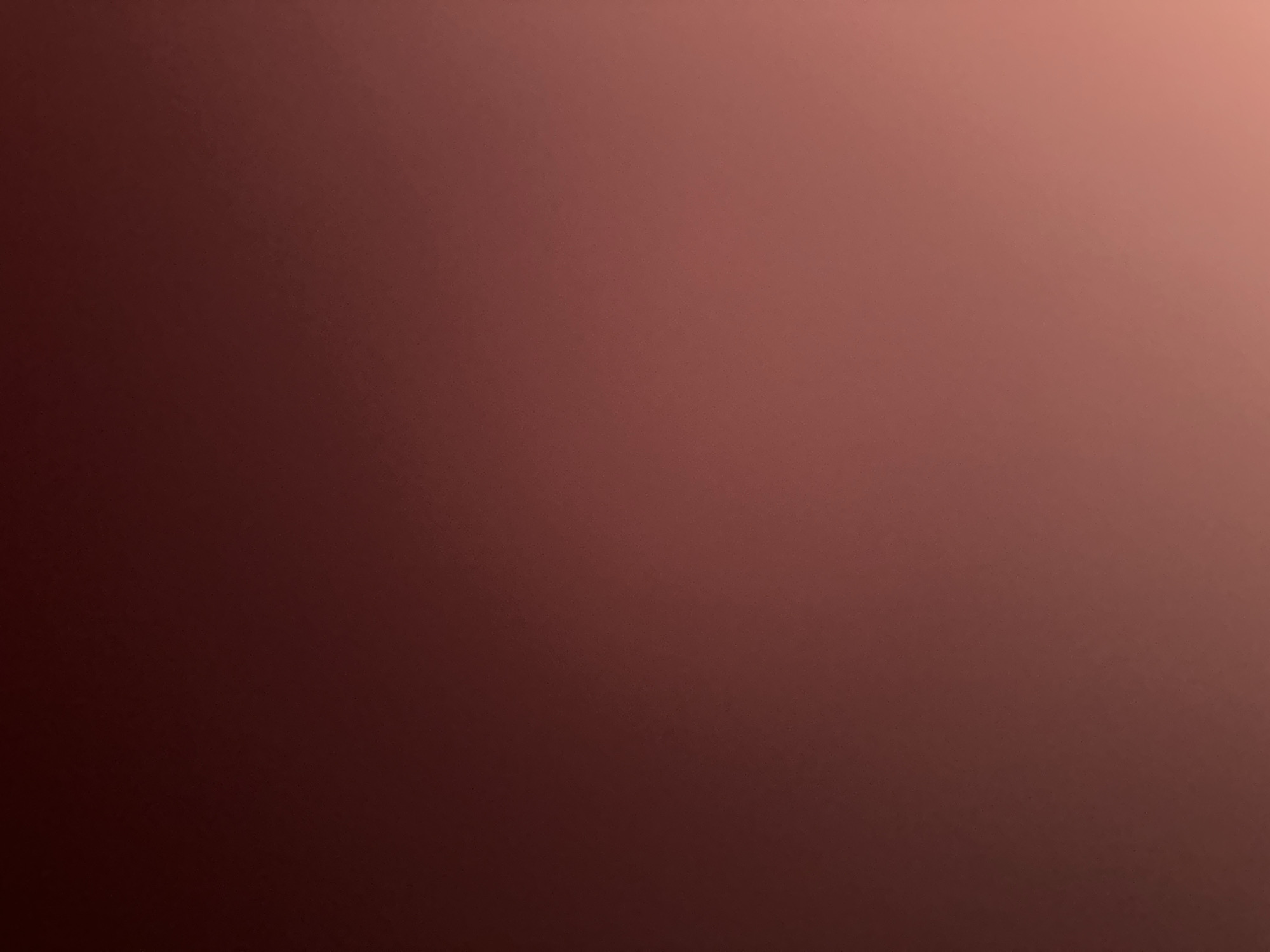 This is a media file that appears to be a close-up of a textured surface, possibly fabric or a painted wall, exhibiting a gradient of reddish-brown to a lighter peachy-brown hue. The texture is subtle, with fine, evenly distributed speckles or noise, suggesting it might be a digital image with added grain or a photograph of a material with a slightly rough surface. There are no discernible subjects, objects, scenes, or activities taking place. The lighting appears to be soft and diffused, creating a gentle transition in color from left to right, with the darker tones on the left and the lighter tones on the right, suggesting a light source originating from the upper right. There is no visible text, no indication of the time of day, weather, or specific location cues, beyond the provided context of Belgrade, Serbia, which is not visually evident in the image itself. The overall impression is one of abstract color and texture.