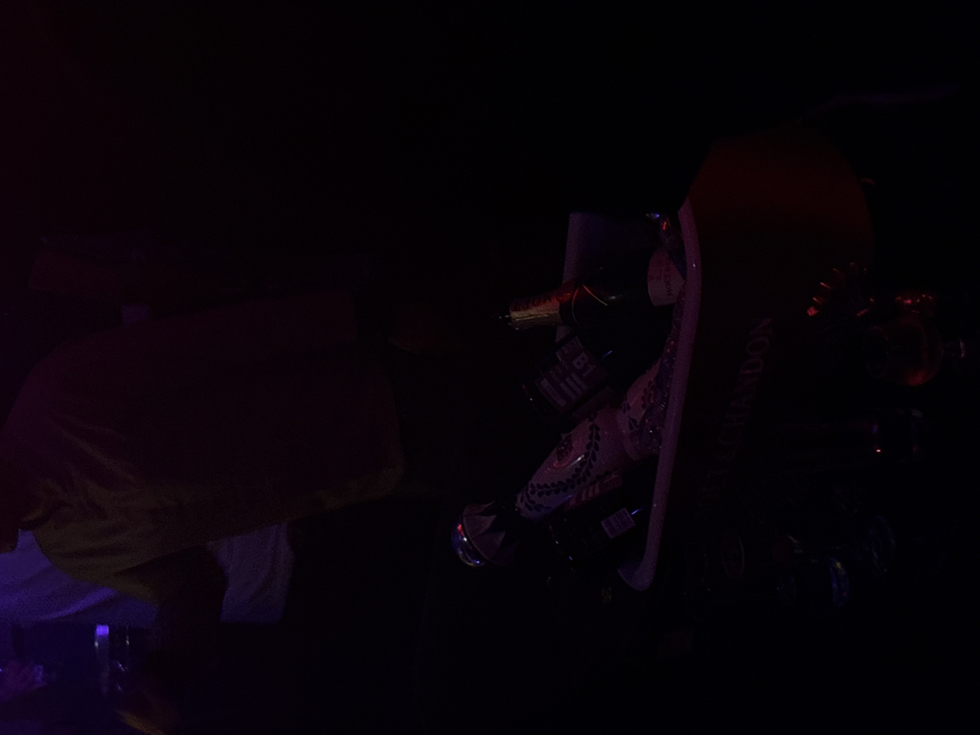 In a dimly lit indoor setting in Mexico City, Mexico, a person wearing a tan shirt is partially visible in the lower left of the frame. A bucket overflowing with bottles of Moët & Chandon champagne sits on the right.