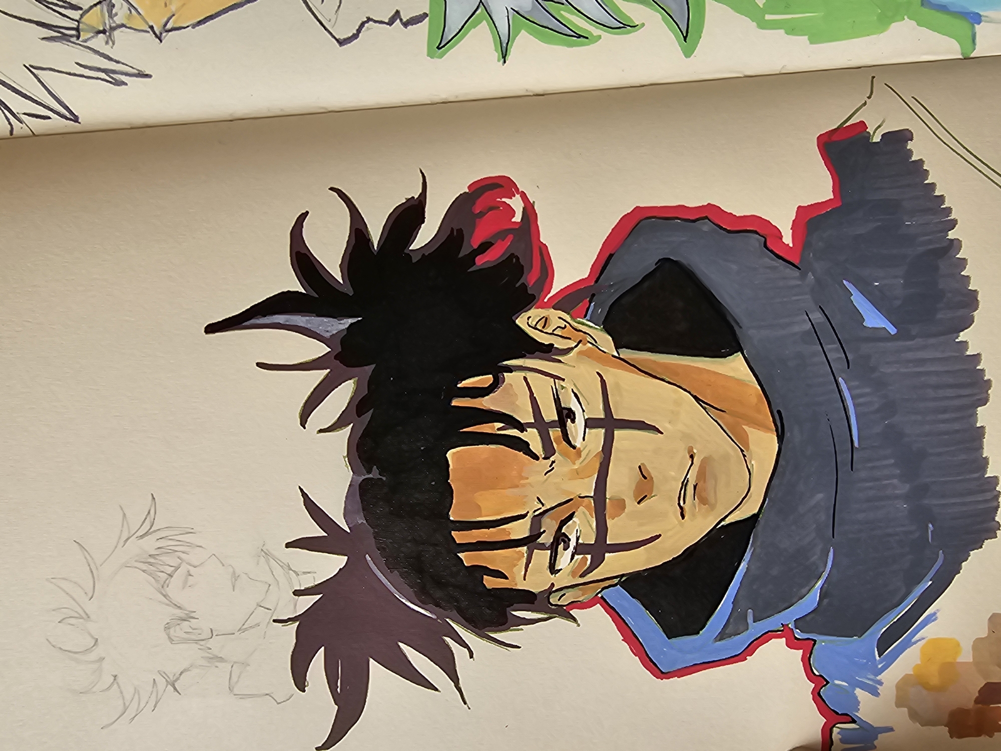 The image shows an open sketchbook on a neutral-toned surface, likely a table. The sketchbook contains a partly colored illustration of a character with spiky black hair, tan skin, and dark markings on the face. The character is wearing a dark hooded jacket with red and blue outlines. The character's face is tilted.
Next to the colored illustration, on the left side, there's a pencil sketch of the same character in a similar pose. Above the main illustration, the upper part of a colored illustration on the previous page of the sketchbook is visible. Green, white, and yellow elements are visible. The context does not provide information regarding the location in Burgas, Bulgaria.
