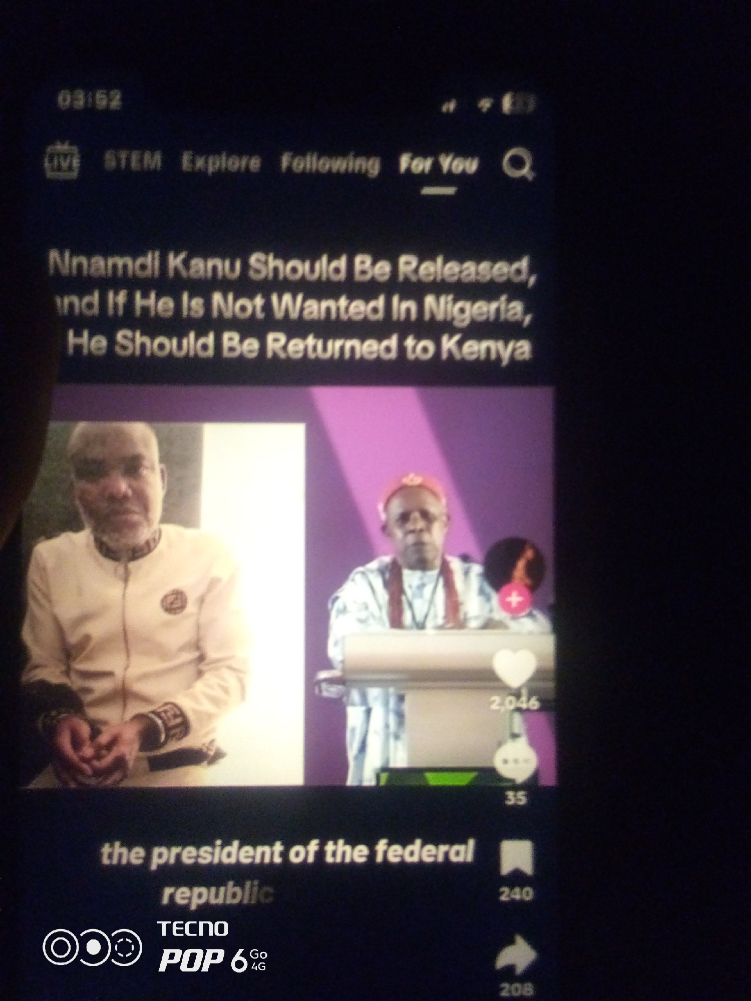 The image displays a screenshot of a video with text overlaid. At the top left, a timestamp reads "03:52". Below this, a navigation bar shows "LIVE", "STEM", "Explore", "Following", and "For You", with a search icon on the right. The main text reads: "Nnamdi Kanu Should Be Released, and If He Is Not Wanted in Nigeria, He Should Be Returned to Kenya".
The video shows two individuals. The person on the left is a middle-aged man with short gray hair and a beard, wearing a light-colored, possibly white or cream-colored, jacket with dark trim and a circular emblem on the chest. His hands appear to be cuffed in front of him. He is looking directly at the camera. The person on the right is wearing a red cap and a patterned robe with red sashes, and also appears to be looking forward. A heart icon with "2,046" below it, and a comment icon with "35" below it are visible on the right side of the video frame.
Below the video, more text is visible: "the president of the federal republic". At the bottom left, a logo for "TECNO POP 6 4G" is present. The background of the video is a mix of solid purple and some green elements. The overall scene appears to be a digital interface, likely from a social media platform or video-sharing app. The specific location in the city of Howayi, Nigeria, cannot be determined from the provided image.