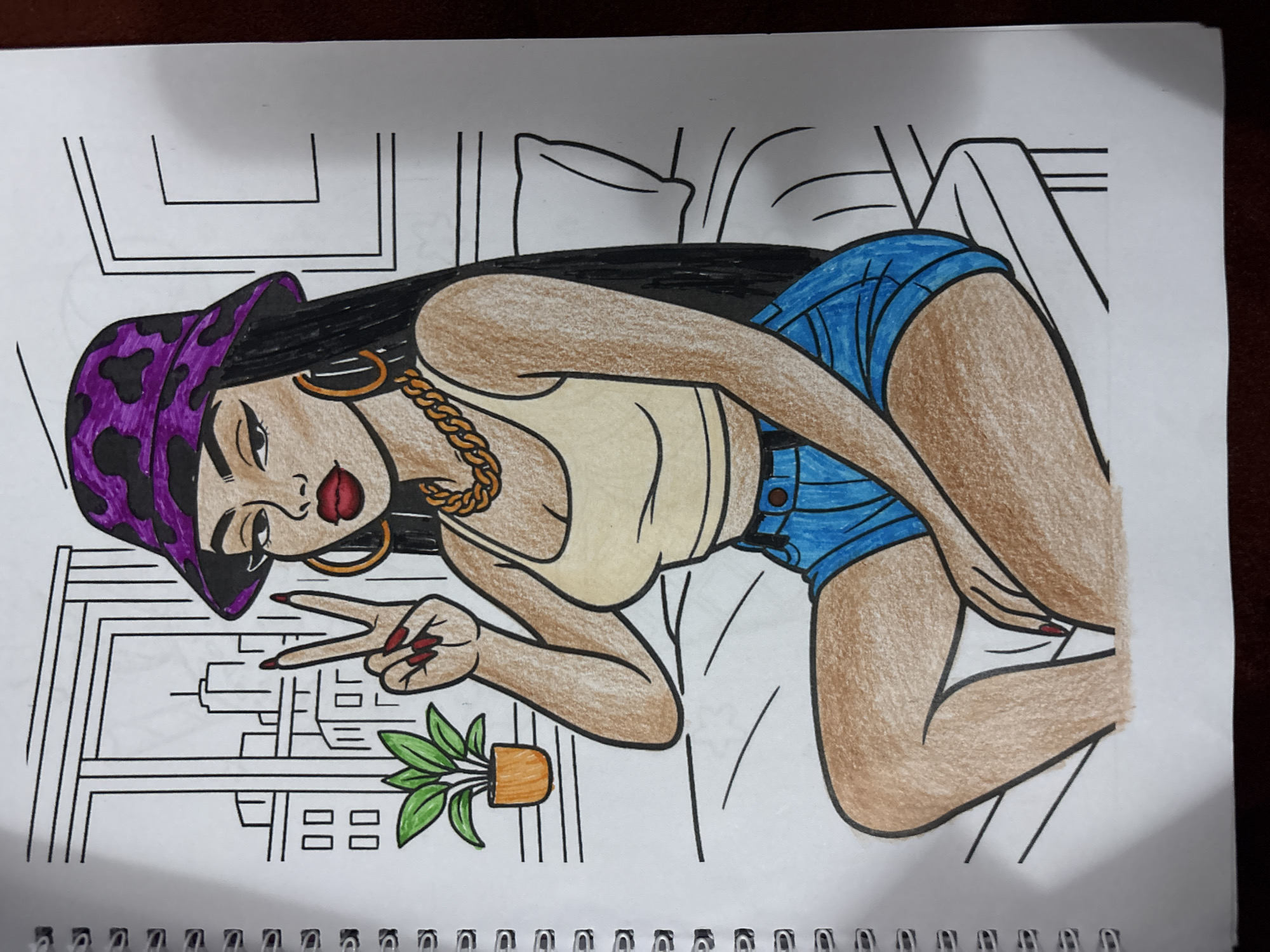 This is a coloring book page featuring a stylized illustration of a young Black woman with long, dark hair, wearing a purple bucket hat with black leopard print, large gold hoop earrings, a gold chain necklace, a light yellow tank top, and blue denim shorts. She is sitting with her legs crossed, holding up two fingers in a peace sign. The background depicts a cityscape seen through a window, a potted plant, and a bed with a pillow. The illustration is partially colored in with crayons, with the woman's skin, clothing, and accessories filled in, while the background remains largely uncolored. The image is on a spiral-bound notebook page. There is no information or context provided about the city of Lafia, Nigeria, or any elements that would place the scene there.