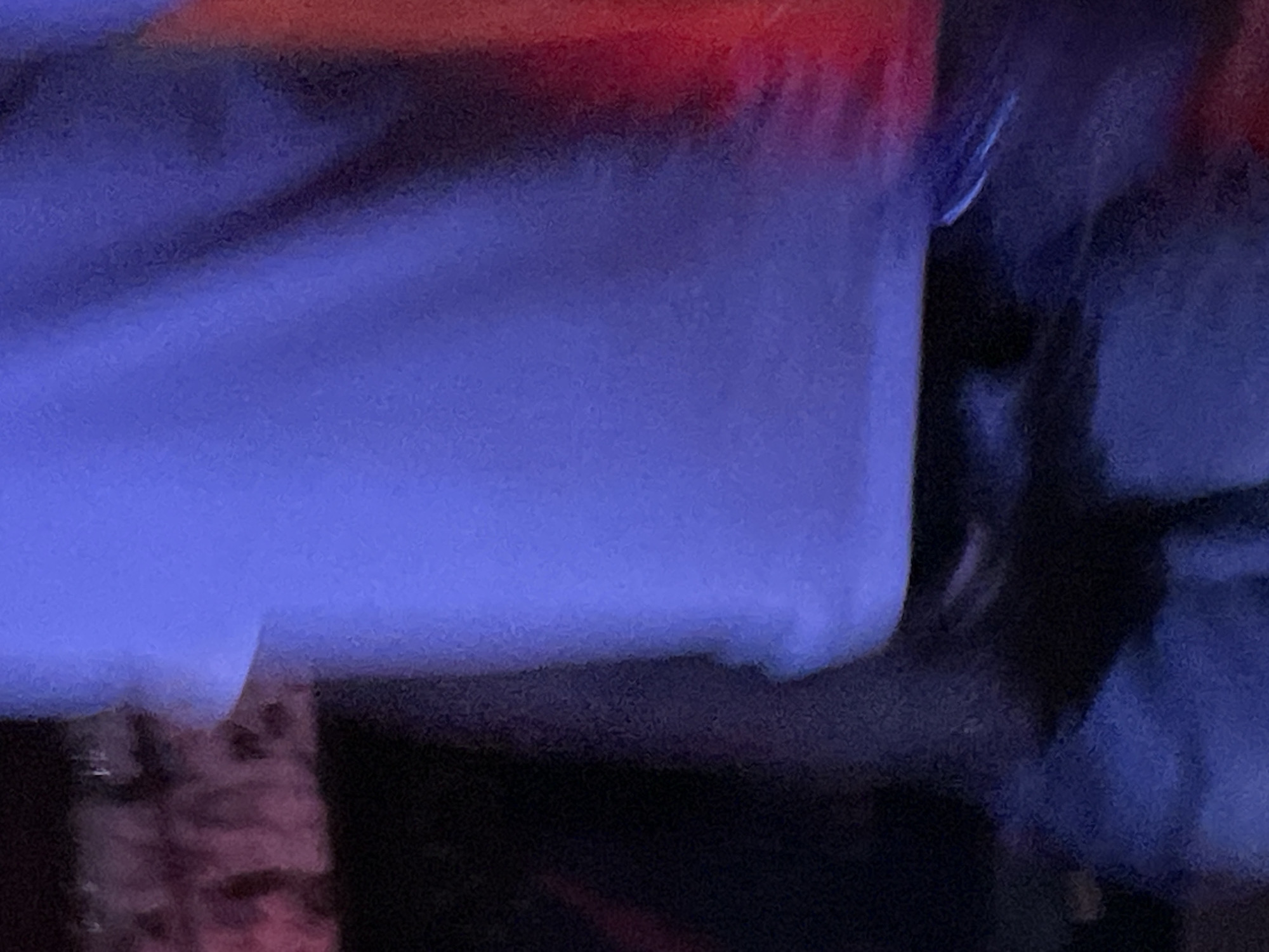 The image is a close-up, abstract shot of textured fabric in shades of blue and red, possibly from clothing or upholstery. The lighting is dim and casts shadows, creating a moody atmosphere. There are no discernible landmarks or details that would place this image in Durumi, Nigeria, or any specific city. The image does not show any people, actions, or interactions.