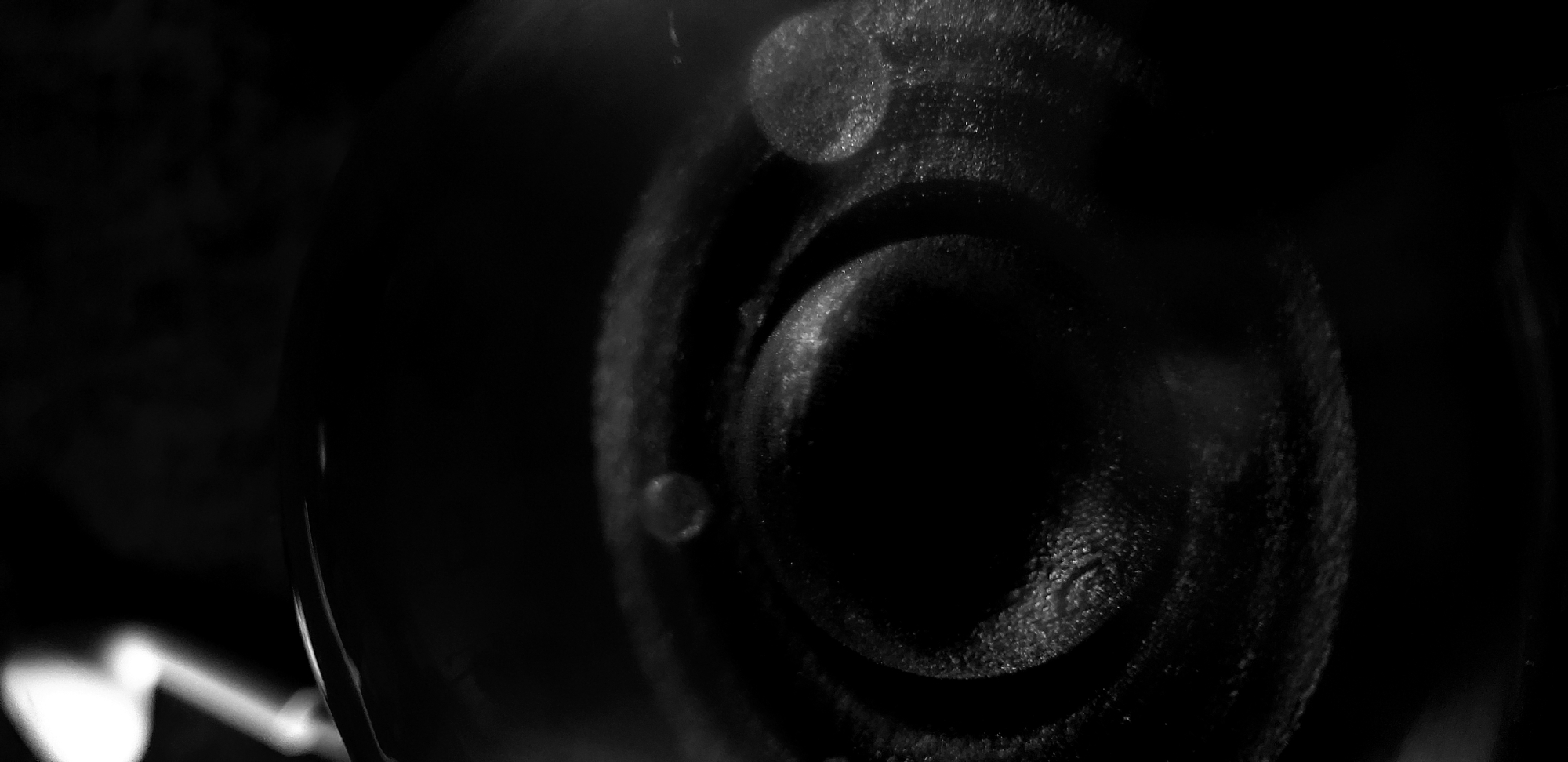 A close-up, black and white photograph shows a circular, dark object with concentric rings. The object appears slightly blurred and has several small, round highlights on its surface. The surrounding area is mostly dark, with some faint light in the lower left corner. The image's depth of field is shallow, with the foreground and background out of focus. The location in Narayi, Nigeria, is not discernible from the image. No people, actions, or interactions are visible.