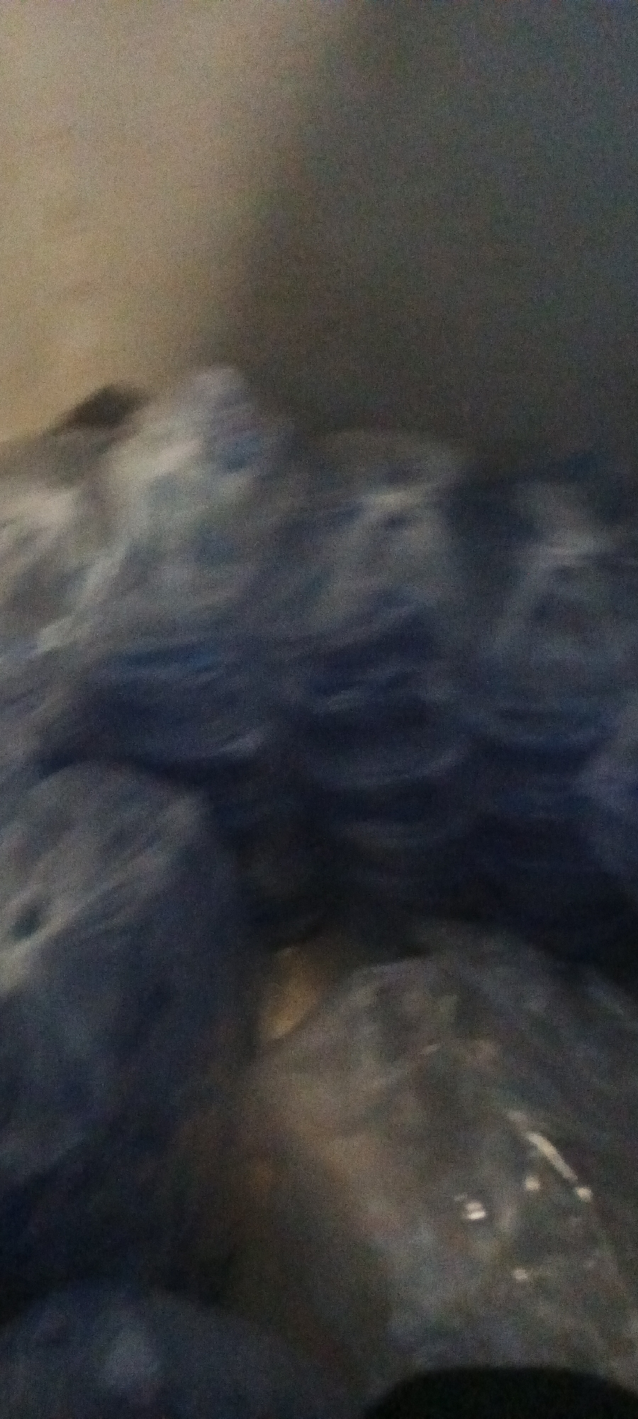 The image shows a pile of water bottles. The location is unknown. The photograph is blurry.
