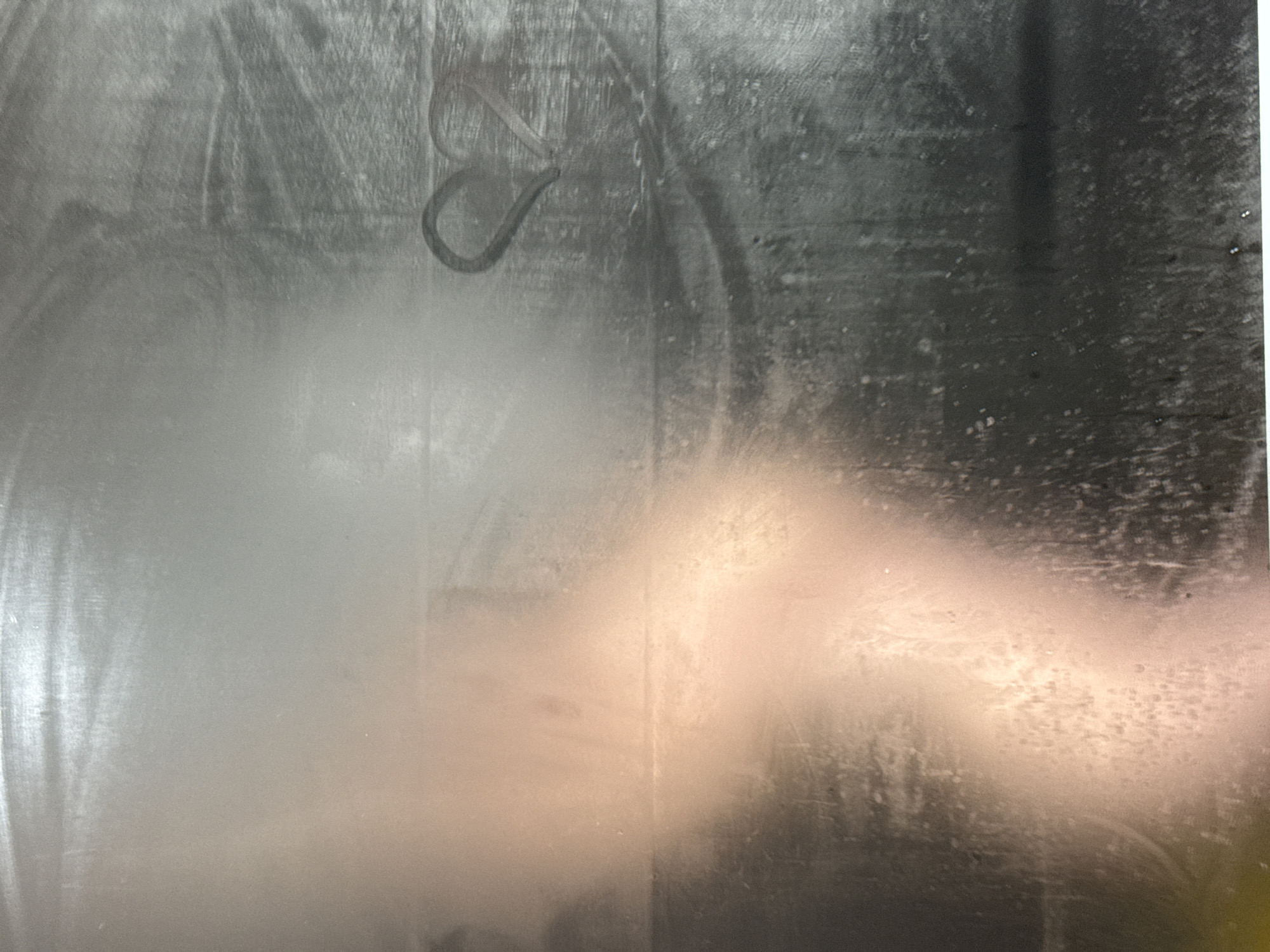 The image shows a misty or wet window, likely indoors. A heart shape is drawn into the moisture on the glass. The location is unknown. No people or specific objects are clearly identifiable within the scene beyond the heart and the window itself. There are no visible actions or interactions, only the static scene of condensation and the drawn heart. The environment is simply the surface of a window with varying degrees of moisture condensation.