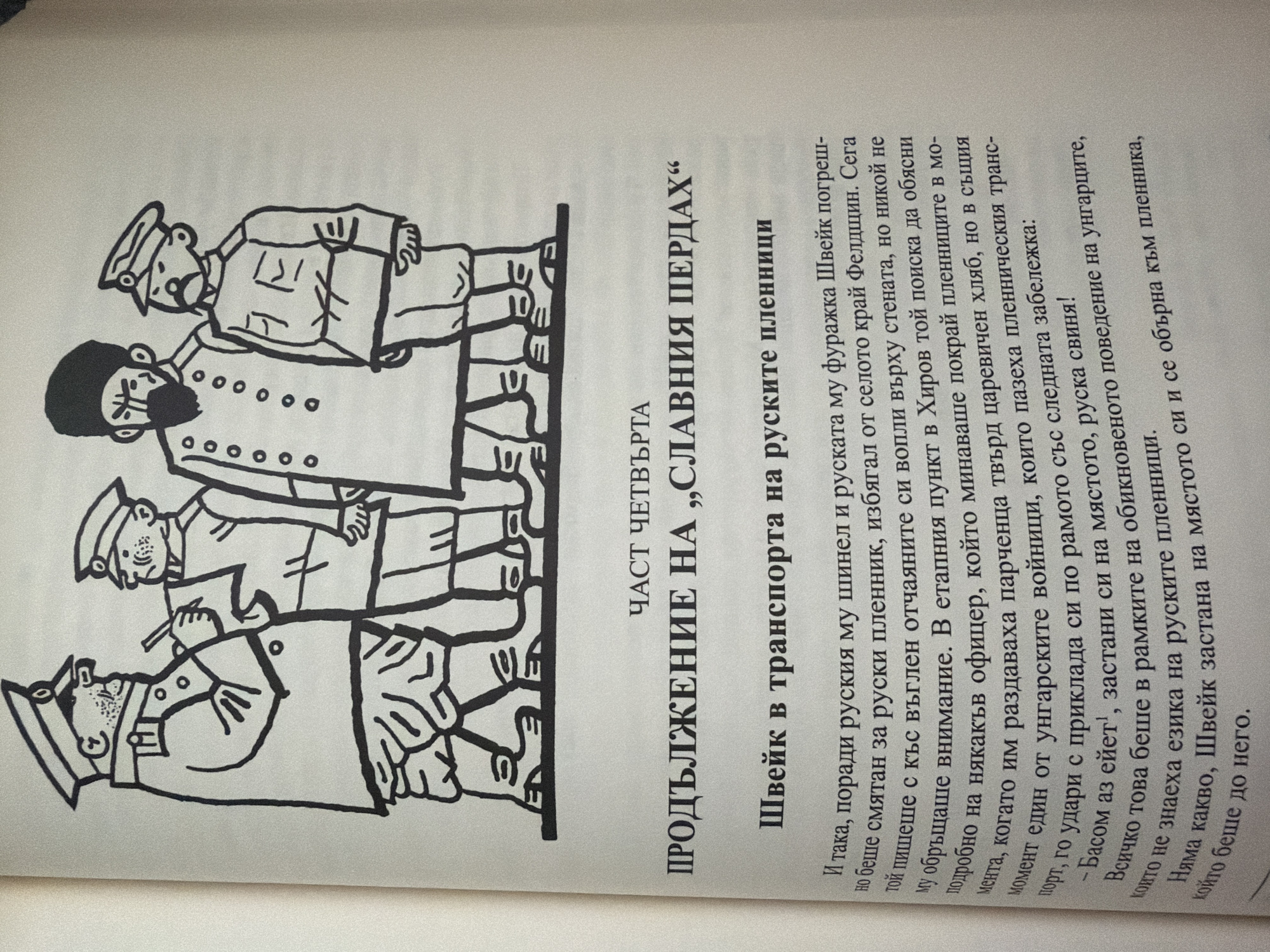 The image is a photograph of a page from a book. The page contains a black and white illustration and text in Bulgarian.
The illustration depicts a group of four men in military uniforms. The man on the far left is wearing a tall cap and a double-breasted coat with epaulets and buttons. He has a stern expression and appears to be holding a pen or pencil and looking at something in his hand. To his right stands another man in a similar uniform, also wearing a cap. To the right of these two, a man with a dark beard and a hat with a brim stands with his arm on the shoulder of another uniformed man, who is looking towards the viewer. The uniformed men are wearing trousers and boots. They are standing on a horizontal line, suggesting a ground surface.
Below the illustration, the page has a header "ЧАСТ ЧЕТВЪРТА" (Part Four) followed by a larger title "ПРОДЪЛЖЕНИЕ НА „СЛАВНИЯ ПЕРДАХ“" (Continuation of "The Good Soldier Švejk").
Beneath the title, there is a subtitle: "ШВЕЙК В ТРАНСПОРТА НА РУСКИТЕ ПЛЕНИЦИ" (Švejk in Transport of Russian Prisoners).
The main body of the text below the subtitles describes an event involving Švejk and Russian prisoners, mentioning a Russian coat and cap, and an interaction with a Hungarian soldier. The text refers to an incident near a village called Feldshutin, and an explanation given to prisoners. It also mentions a Hungarian soldier hitting a prisoner with his rifle butt.
The text is in Bulgarian, and some parts appear to be a narrative or description of events. The image does not contain any information that would allow for the determination of its location within the city of Pazardzhik, Bulgaria.