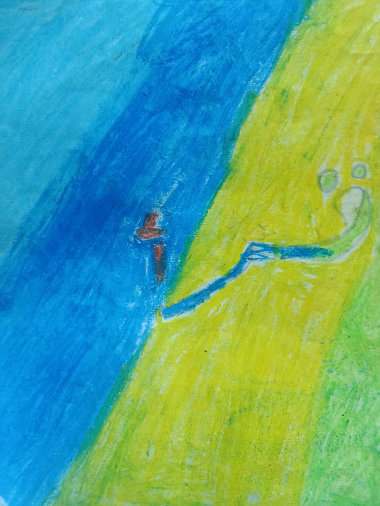 This is a close-up, abstract drawing rendered in crayon or pastel. The image is divided diagonally, with the upper left portion dominated by shades of blue, suggesting sky or water. The lower right portion transitions into vibrant yellow and green, possibly representing land or foliage.
In the blue section, there is a small, brown, cross-like shape. In the yellow and green area, a simplistic, cartoon-like figure is depicted. It has two circular eyes and a curved line forming a mouth, giving it a slightly startled or surprised expression. A thin, blue line extends from the figure's right side, reaching towards the center of the image. The overall style is rudimentary, characteristic of a child's drawing. There is no discernible information about Tambun Magih, Indonesia within the image itself.