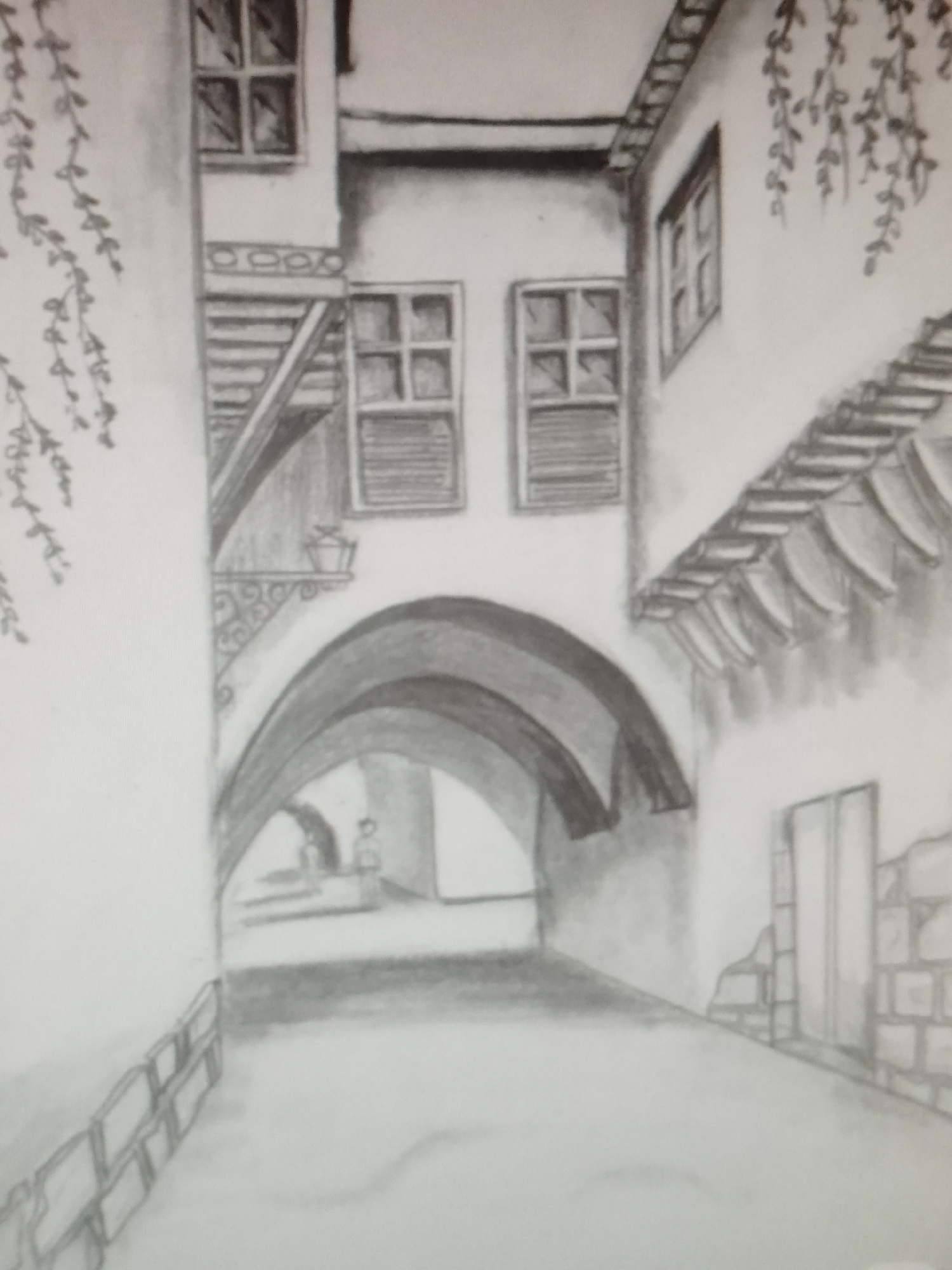 The image shows a pencil drawing of an alleyway in what appears to be an old city. The alleyway is defined by arched passageways leading deeper into the perspective. Buildings flank both sides of the alley, with windows and architectural details suggesting a historic setting. Foliage, possibly vines, hangs from the buildings. The ground is lightly shaded, indicating the alleyway surface. There's a suggestion of a figure further down the alley. The scene is monochromatic and focuses on the play of light and shadow to create depth.