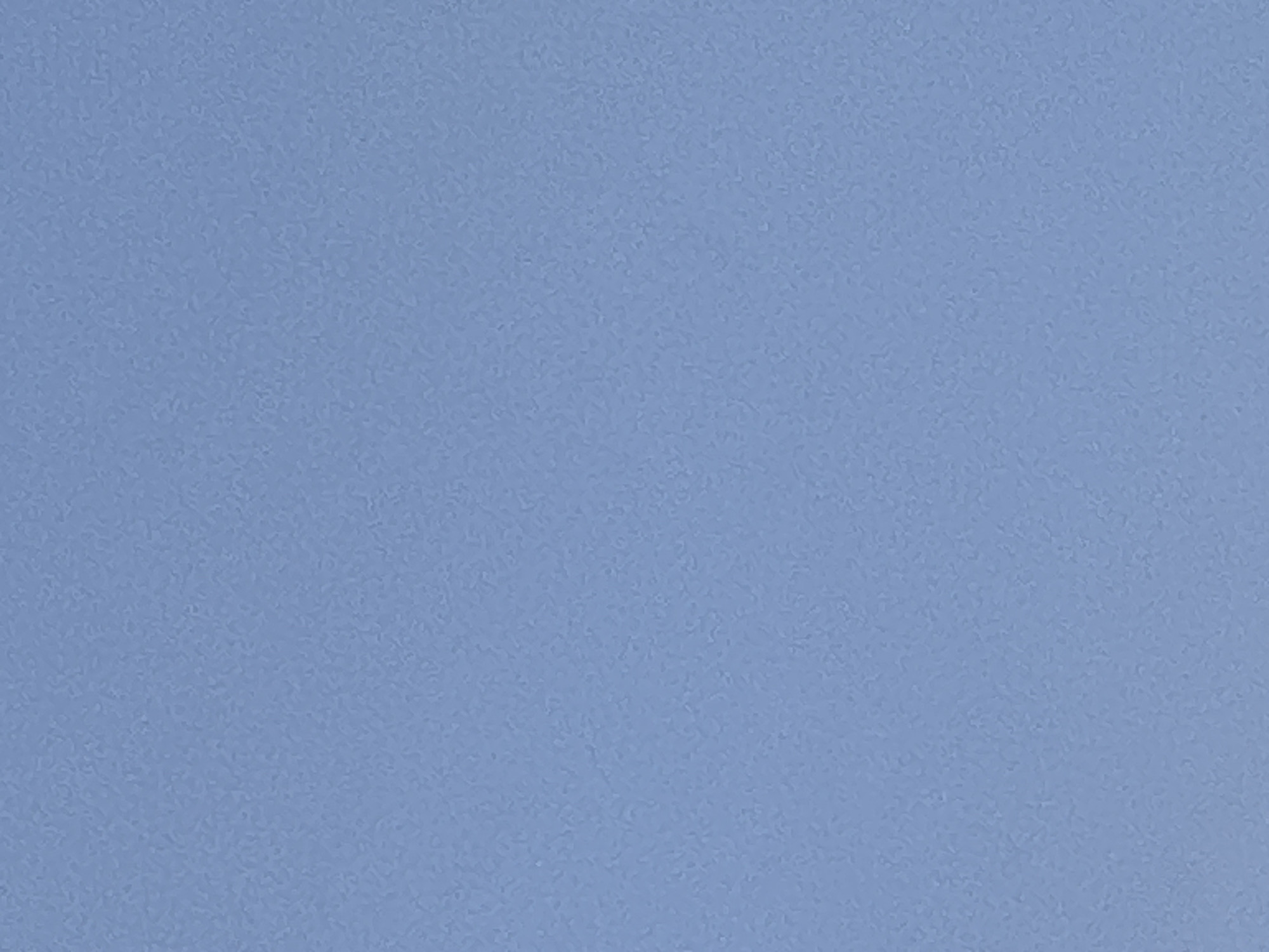 The image is a close-up, abstract shot of a textured, light blue surface. The texture appears to be granular or slightly mottled, consistent with a painted wall, fabric, or possibly a sky. There are no discernible objects, people, or environmental features that would indicate a specific location, including Plesetsk, Russia. The lighting appears to be even, with no strong shadows.
