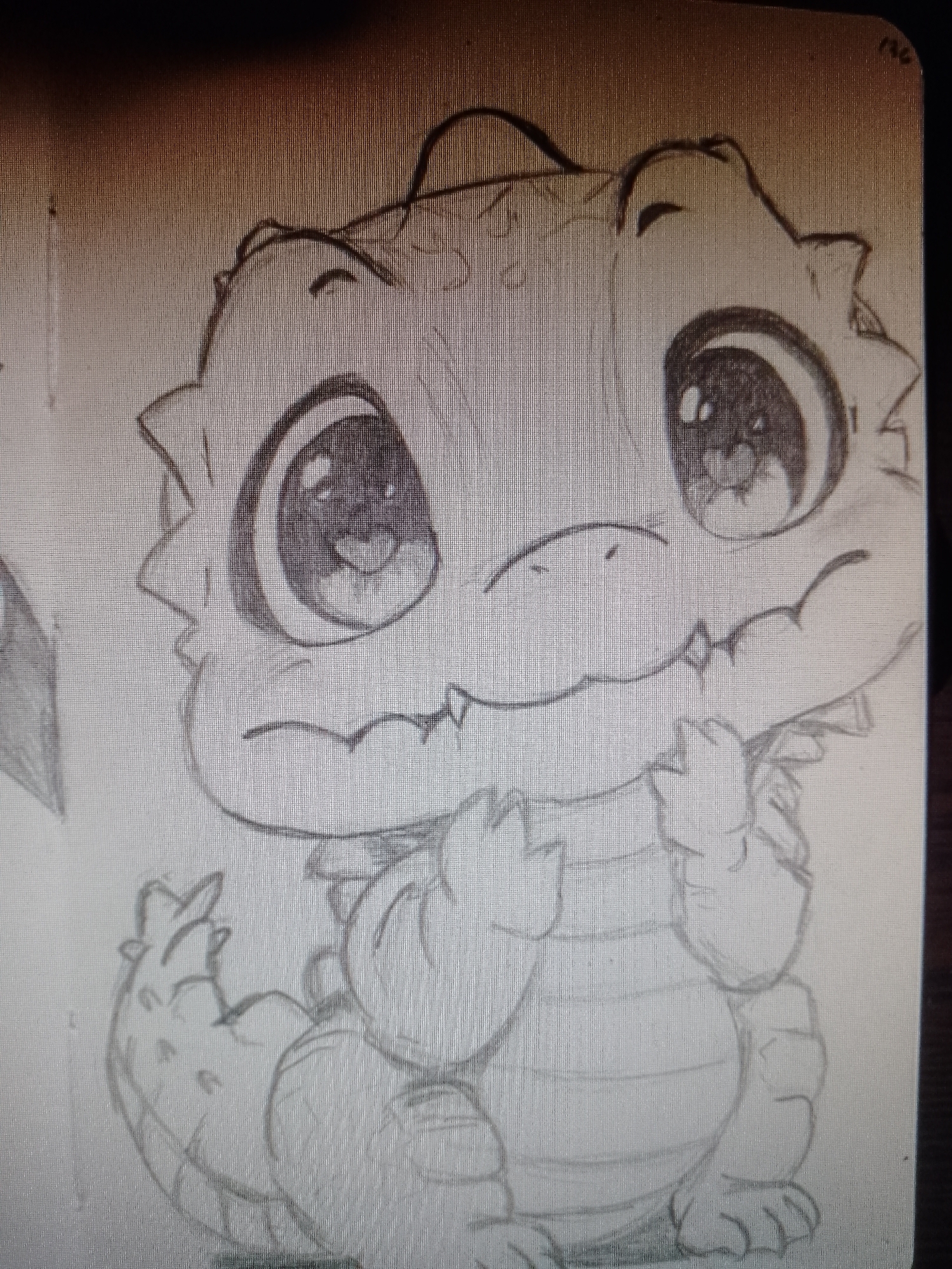 The image is a pencil sketch of a stylized, cartoon-like baby dragon. The dragon has large, round eyes with prominent pupils. It has a small, slightly upturned snout and a mouth with small, pointed teeth. The dragon is sitting in a seated position with its hands raised near its chest. Its body has scales and segments. The background is plain paper.