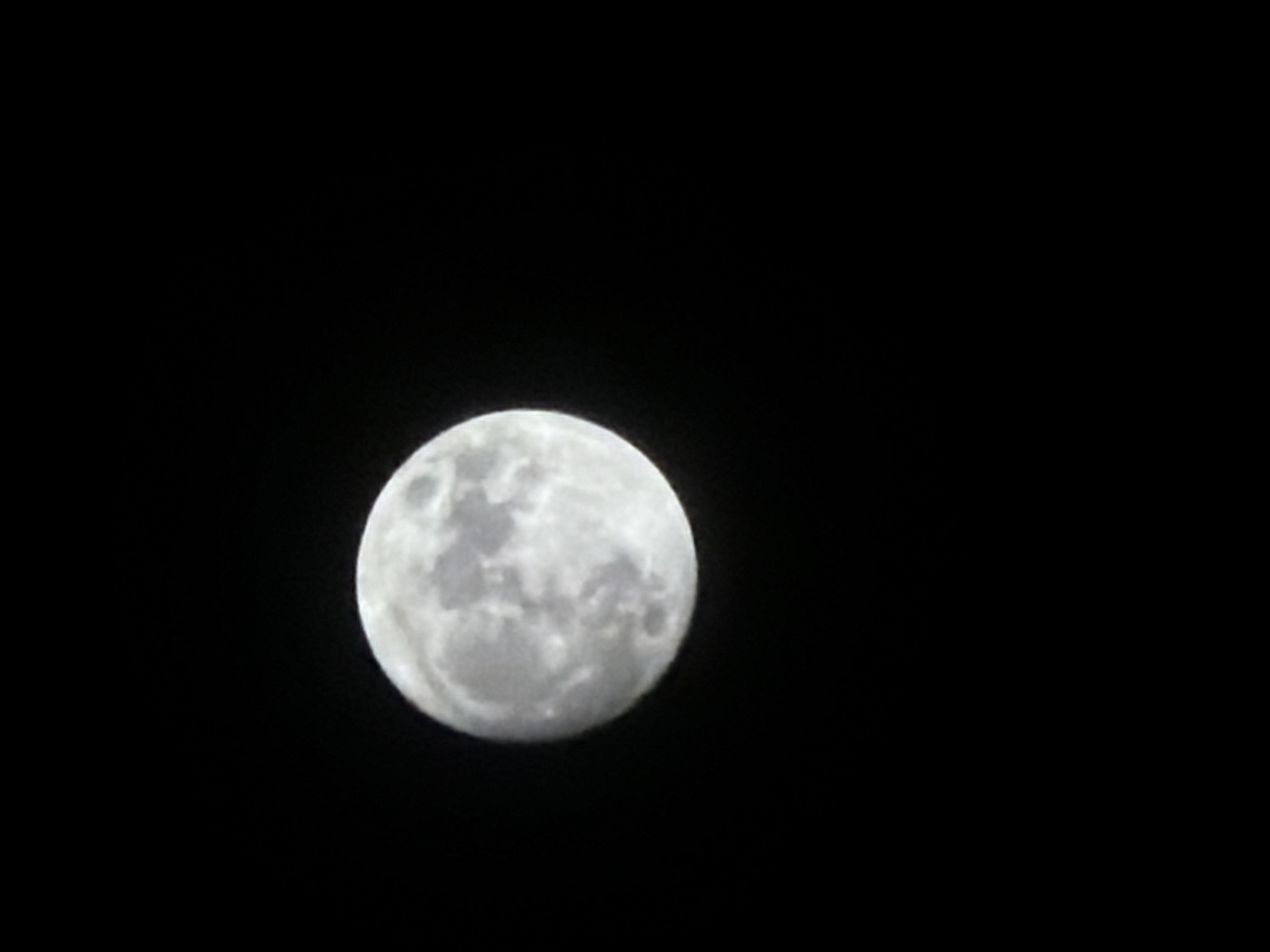 A close-up shot of a nearly full moon is set against a completely black sky. The moon is the only visible object. The location in Burgas, Bulgaria is not discernible from the image.
