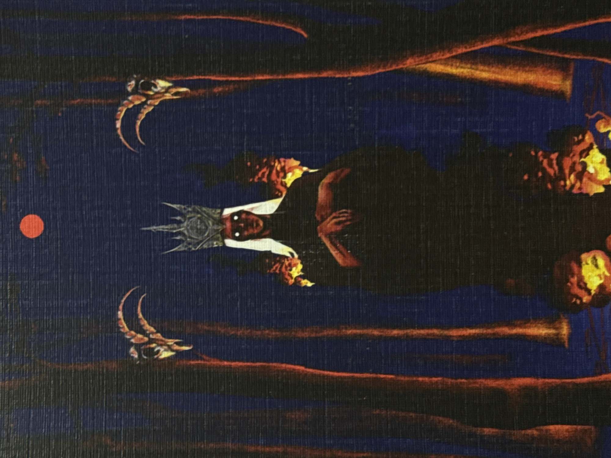 The image depicts a dark, mystical scene with a central figure wearing a crown and having glowing white eyes. The figure is cloaked and appears to be holding their hands together. Flanking the central figure are two goat skulls with horns. In the background, there are tall, dark, tree-like forms with fiery red and orange highlights, suggesting a forest at night or a firelit environment. A small, red, circular object, possibly the moon or a celestial body, is visible in the upper portion of the image. The overall atmosphere is eerie and suggestive of a ritual or supernatural event. There is no indication of the city of Cork, Ireland, or any urban setting.