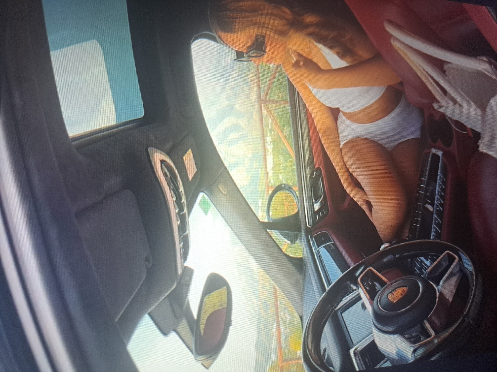 The image shows the interior of a Porsche SUV, focusing on the driver's side. A woman wearing a white bikini is seated in the driver's seat. The car has a sunroof and red leather interior. The steering wheel features the Porsche emblem. The car appears to be located in a mountainous or hilly area with some buildings visible through the car windows. The city mentioned is Yerevan, Armenia, however, there is no visible evidence to determine that is the case.