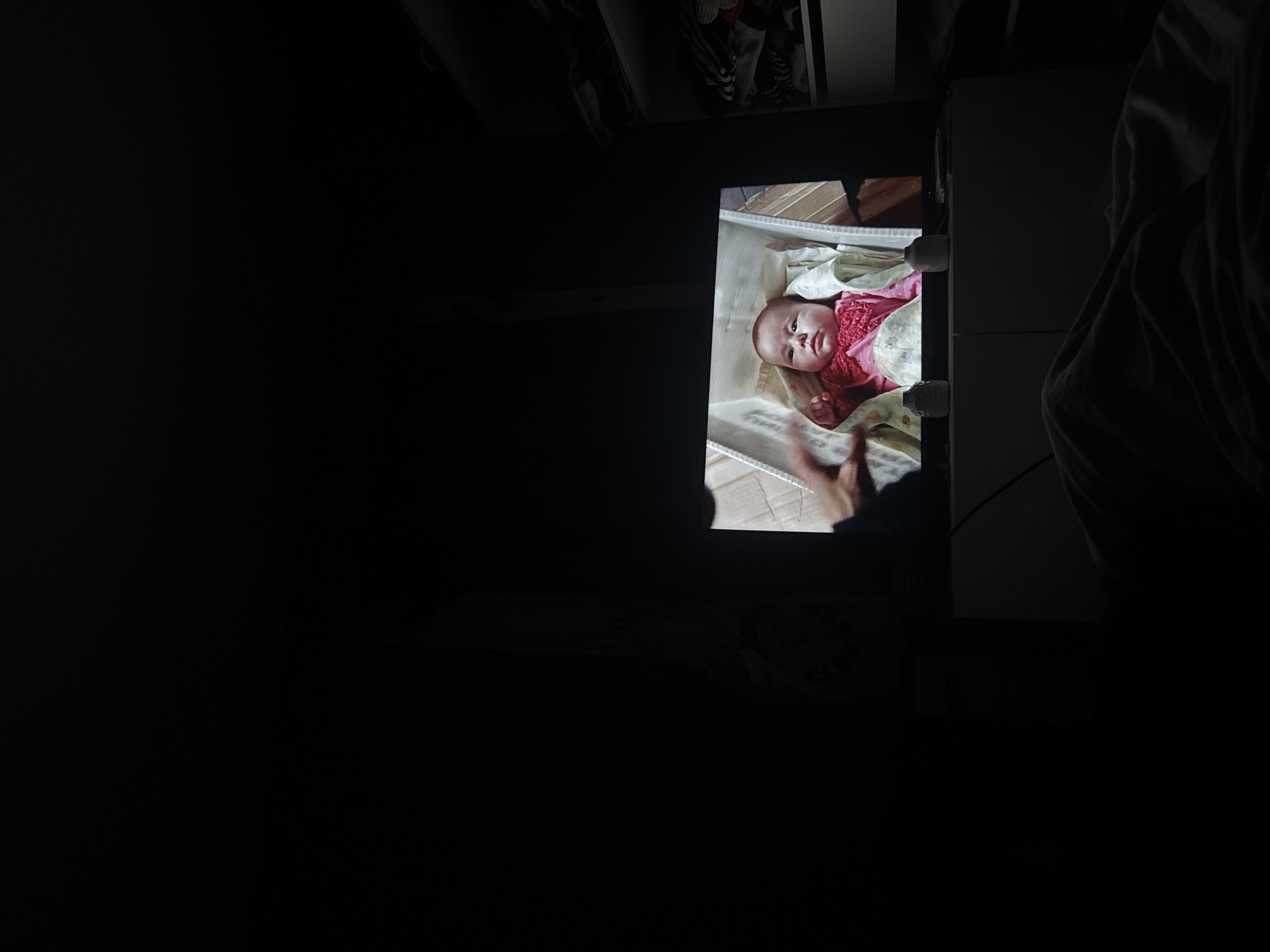 A baby is lying in a box inside a dark room. The room appears to be located inside a home. The city of Lannoy, France is not apparent in this image.