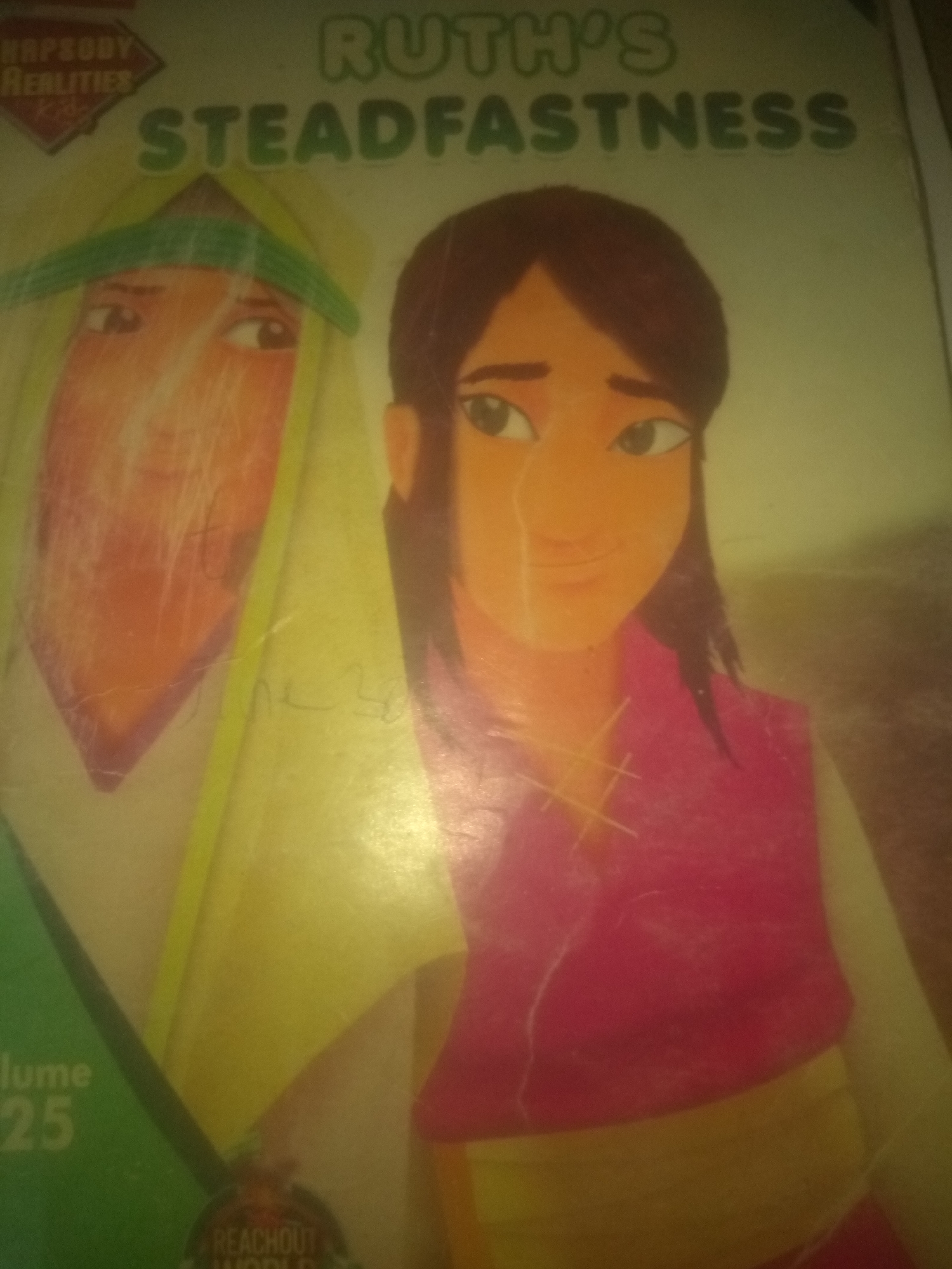 The image is a close-up, slightly blurry photograph of a book cover. The title, "RUTH'S STEADFASTNESS," is prominently displayed in green lettering across the top of the cover. Below the title, two illustrated characters are depicted. The character on the left appears to be wearing a yellow headdress and has a tan face. The character on the right has dark hair, dark eyes, and is wearing a pink garment with a yellow band around the waist. The background is a light green color. In the bottom left corner, text indicates "lume 25," and at the very bottom, a circular logo with the text "REACHOUT WORLD" is partially visible. The photograph has a yellow cast and some visible scratches on its surface. No specific location in Jauro Yinu, Nigeria, is discernible from the image.