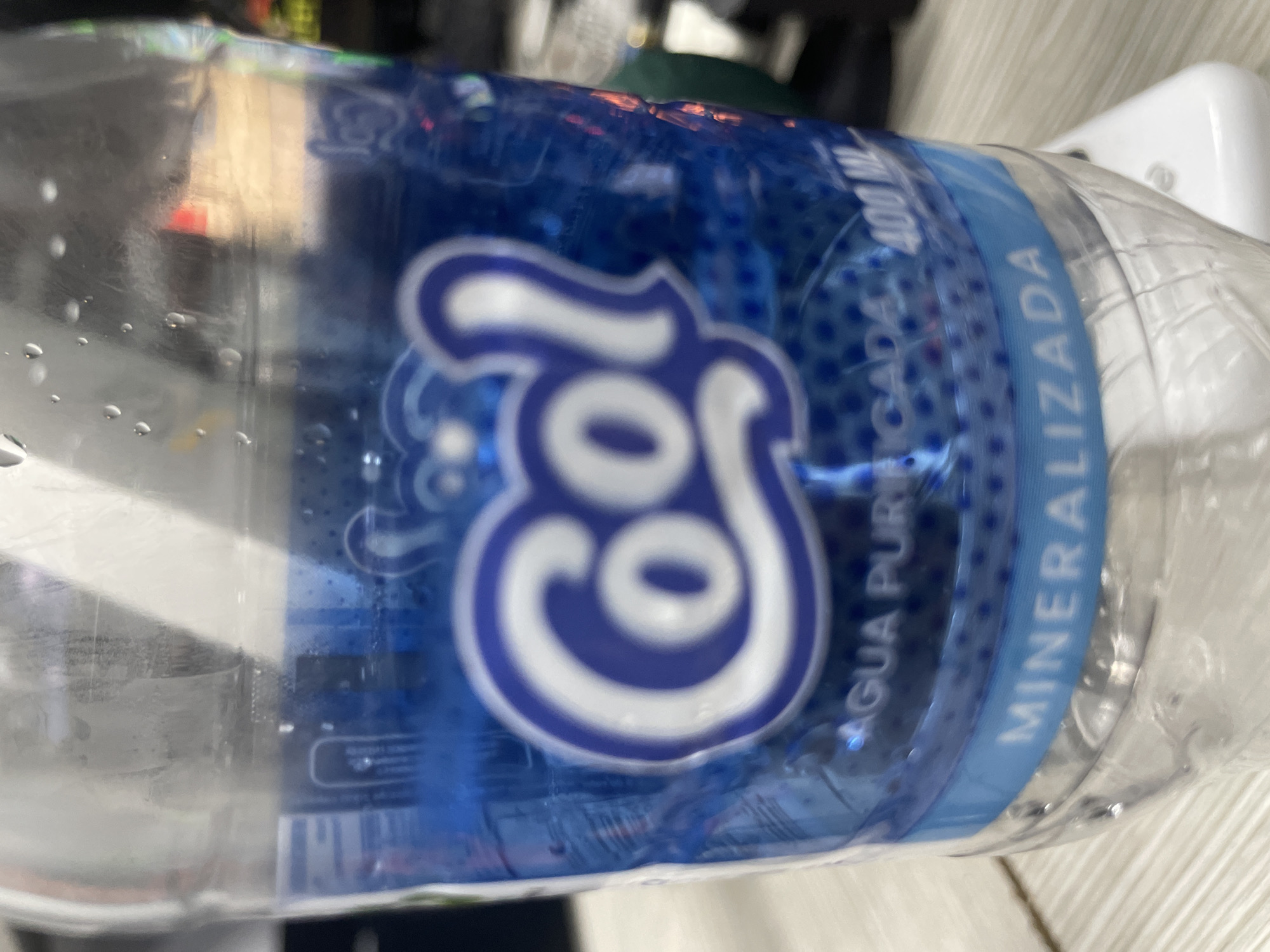 The image shows a close-up of a "Cool" brand water bottle, specifically labeled "Agua Purificada Mineralizada" (Purified Mineralized Water). The bottle indicates a volume of 400 ml. Based on the product, the image may have been taken in Porlamar, Venezuela, as "Cool" is a brand sold in the country.