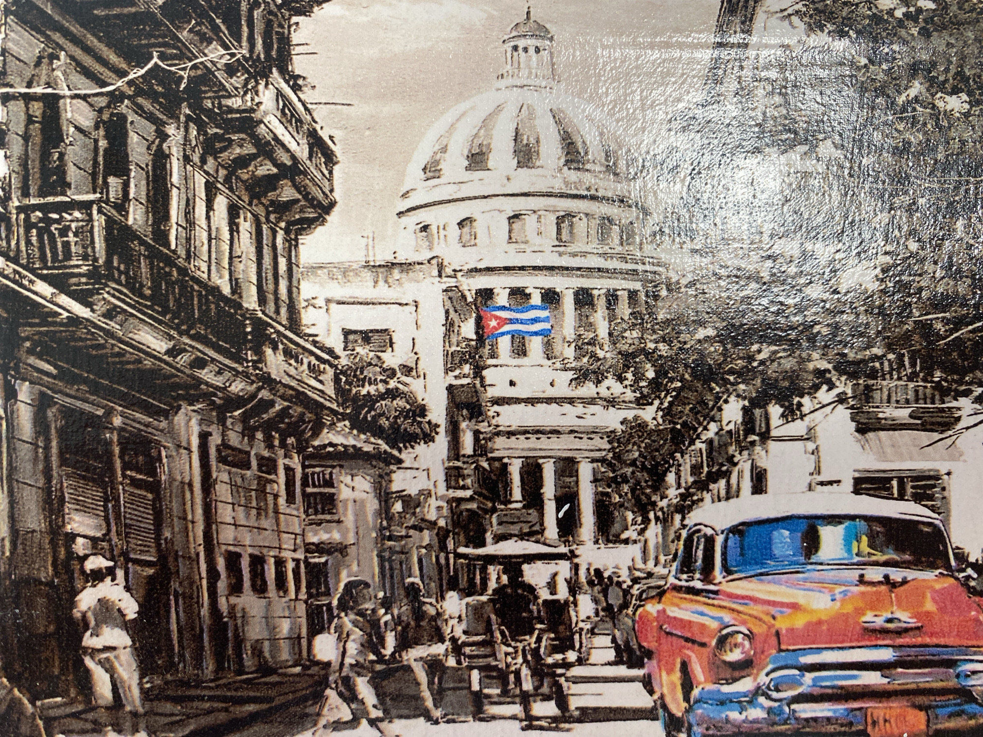 This is a painting depicting a street scene in Havana, Cuba. The primary subjects are a classic red and white car in the foreground, a large domed building in the background with the Cuban flag displayed, and several people walking along the street. The architecture suggests an older, possibly European influence with balconies and ornate facades on the buildings. The painting is rendered in a style that blends black and white with selective color, most notably on the car and the Cuban flag.
The scene appears to be set during the daytime, with a bright, clear atmosphere suggested by the light. The overall mood is lively, with people engaged in everyday activities, and the vibrant colors of the car and flag add a sense of energy and national pride. The domed building is likely a significant landmark, possibly the Capitol Building in Havana. The presence of classic cars is a strong indicator of the location being Cuba. No visible text is discernable in the painting.