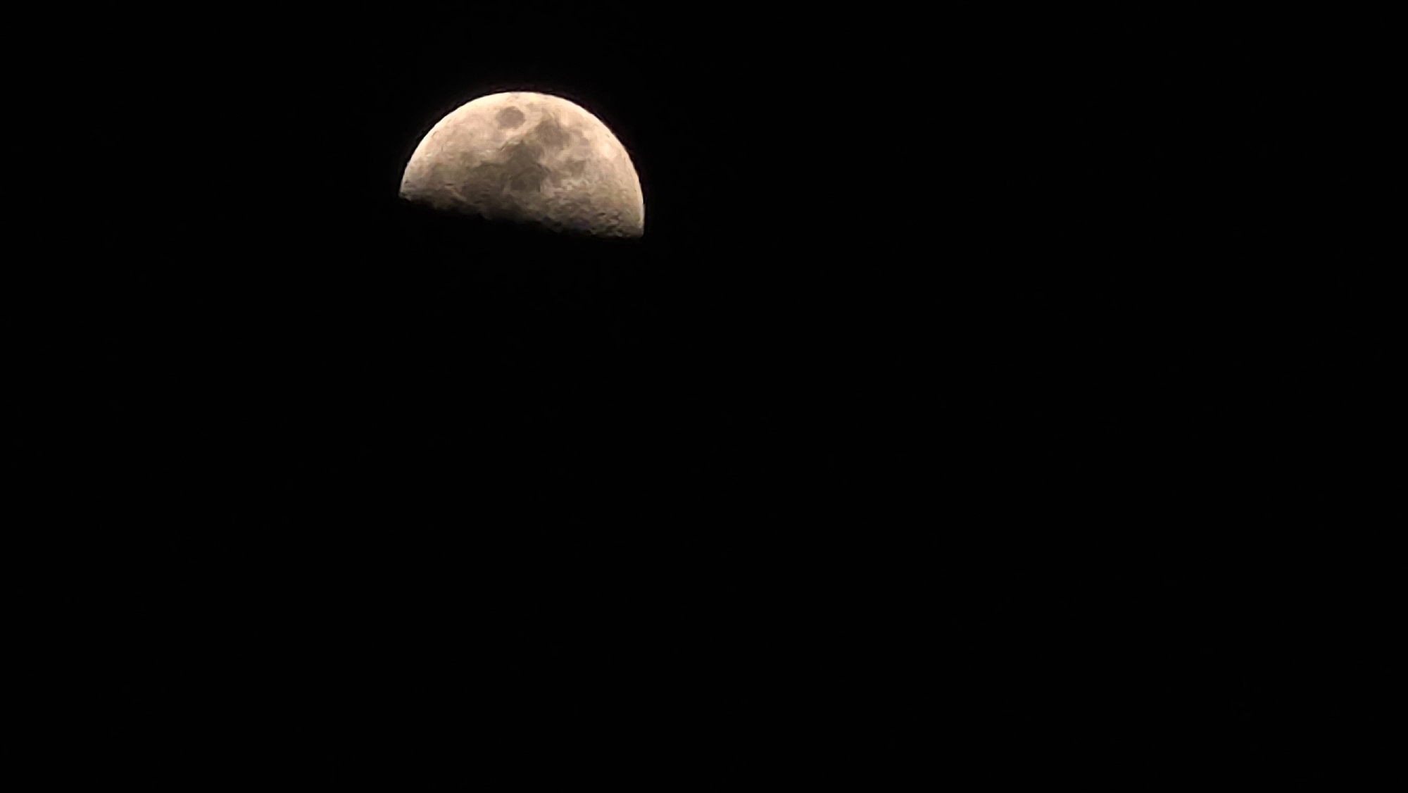 A waxing gibbous moon is visible in a black night sky. The moon is partially illuminated, with the right side being brighter and showing more surface detail such as craters. The moon is positioned in the upper right quadrant of the image. The sky is completely dark and devoid of any other celestial bodies or light sources. There are no people, objects, or environmental elements present other than the moon and the sky. There is no indication of the city of Butor, Moldova in this image.