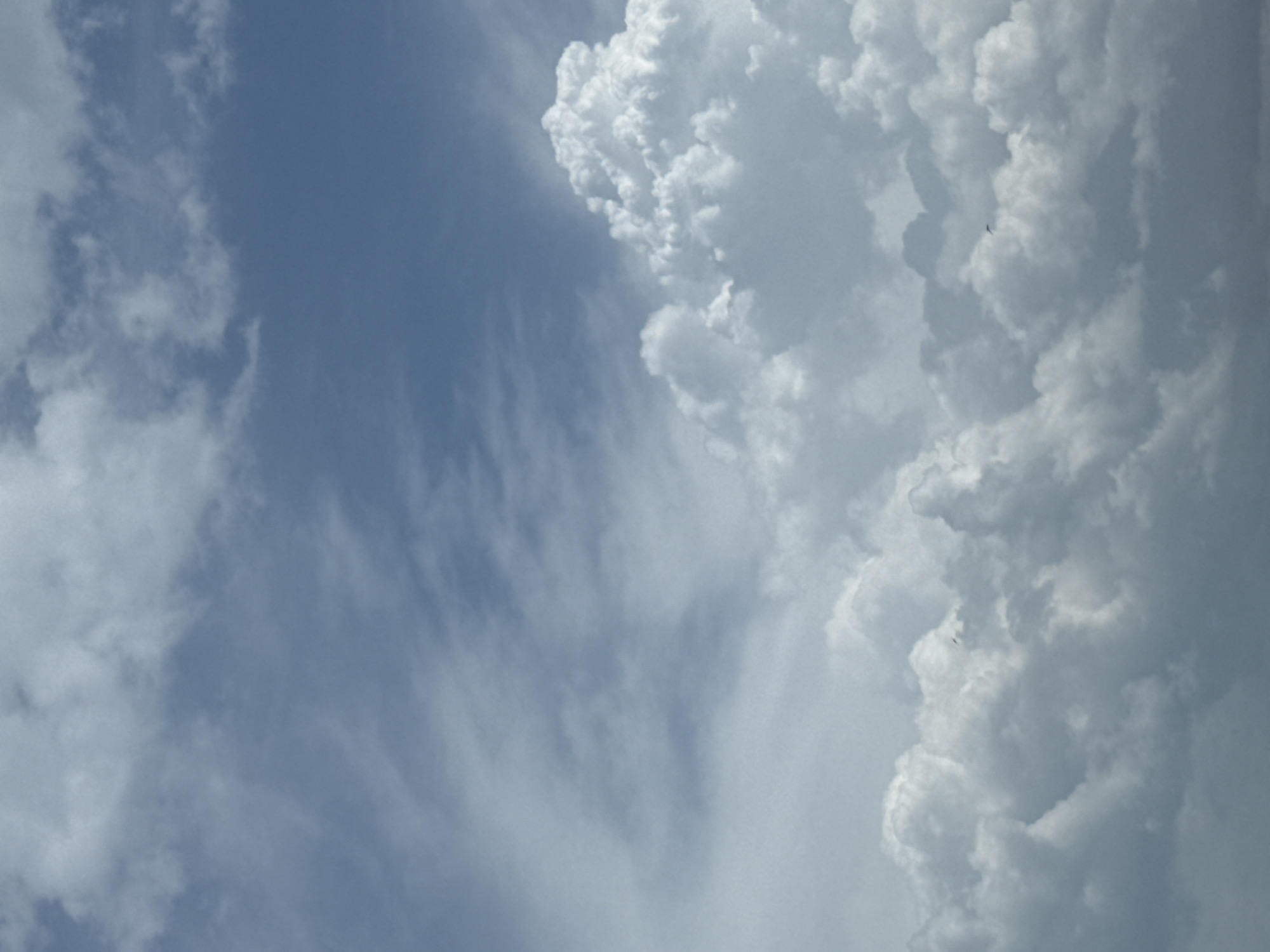 The image shows a sky with white and gray clouds. Part of the sky is light blue. The image was taken outdoors. The city and country are not discernible.