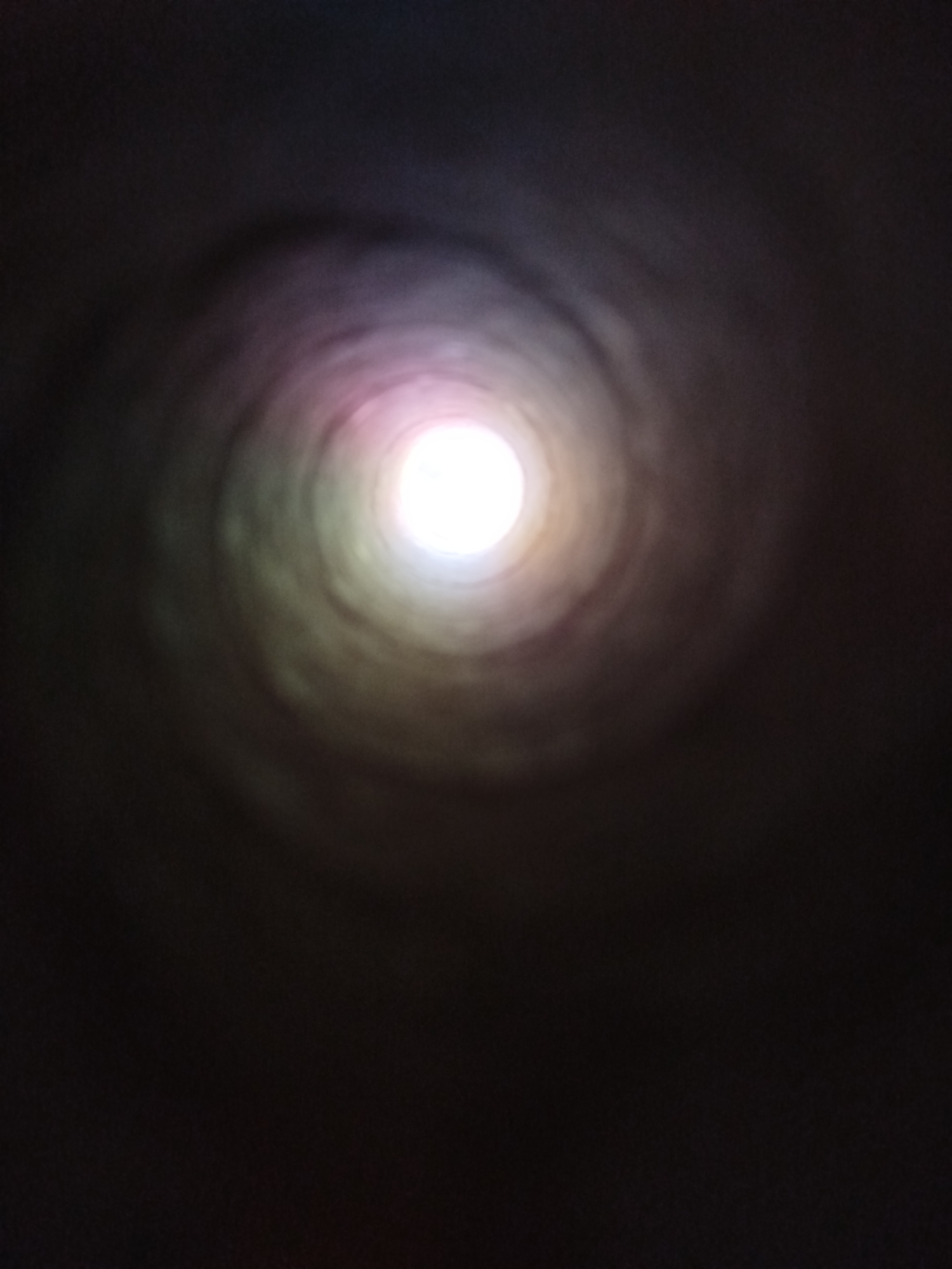 The image depicts a vortex-like tunnel with a bright light at the end. The tunnel walls are dark and appear to be textured. The lighting suggests a transition from darkness to light. There are no visible people, subjects, objects, or interactions. The location in Kremenchuk, Ukraine is not discernible from the image alone. The scene is abstract and does not provide specific contextual information about its environment or purpose.