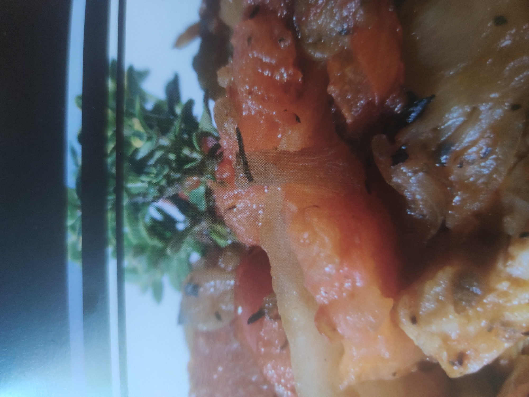 The image shows a close-up of a food dish, possibly containing potatoes, tomatoes, and herbs. The herbs appear to be thyme. The setting or location is unidentifiable.