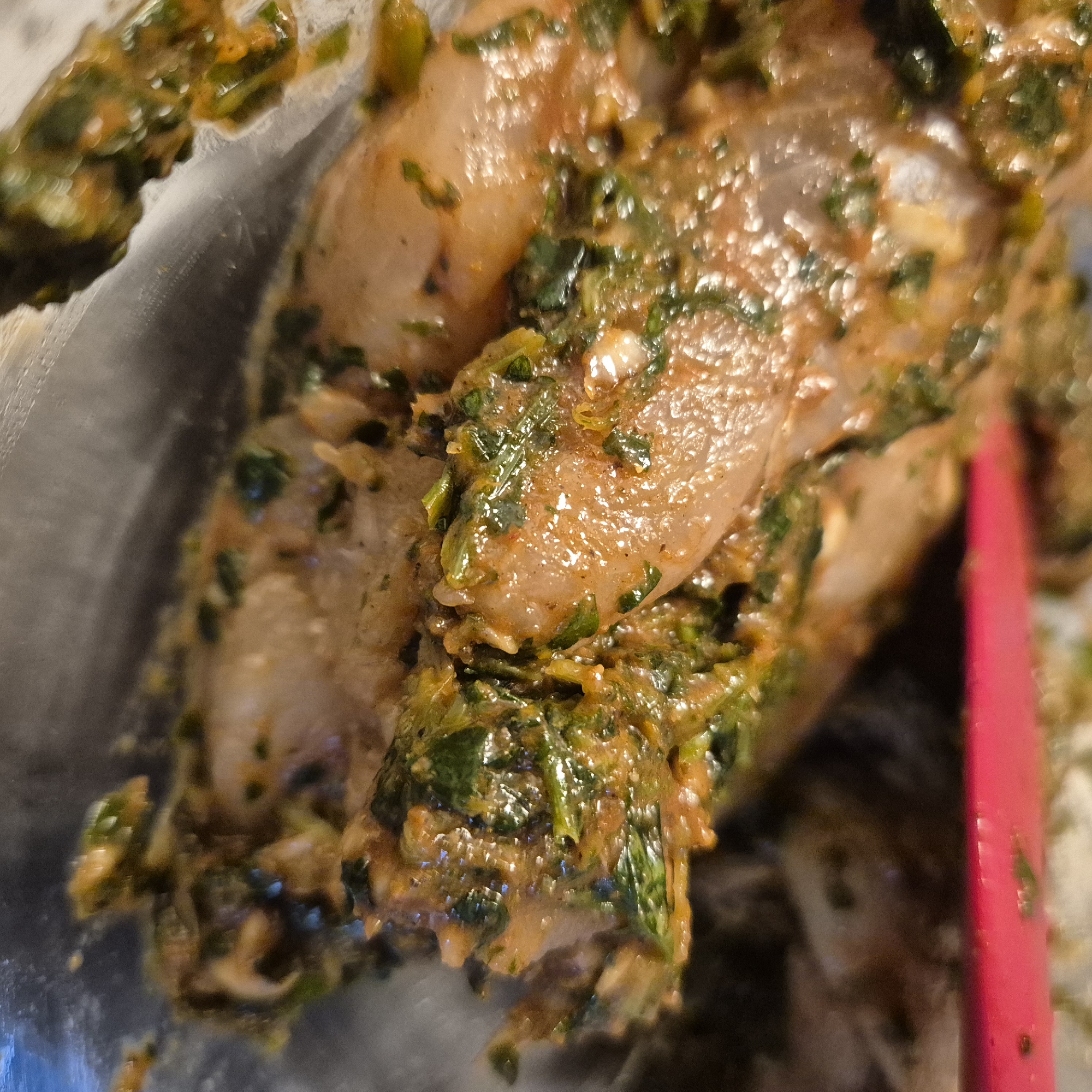 The image shows pieces of marinated chicken, likely in a bowl. The marinade appears to be herb-based, possibly containing parsley and other spices. The overall visual presentation suggests the preparation stage of a meal. There is no context to support this having taken place in Strasbourg, France.