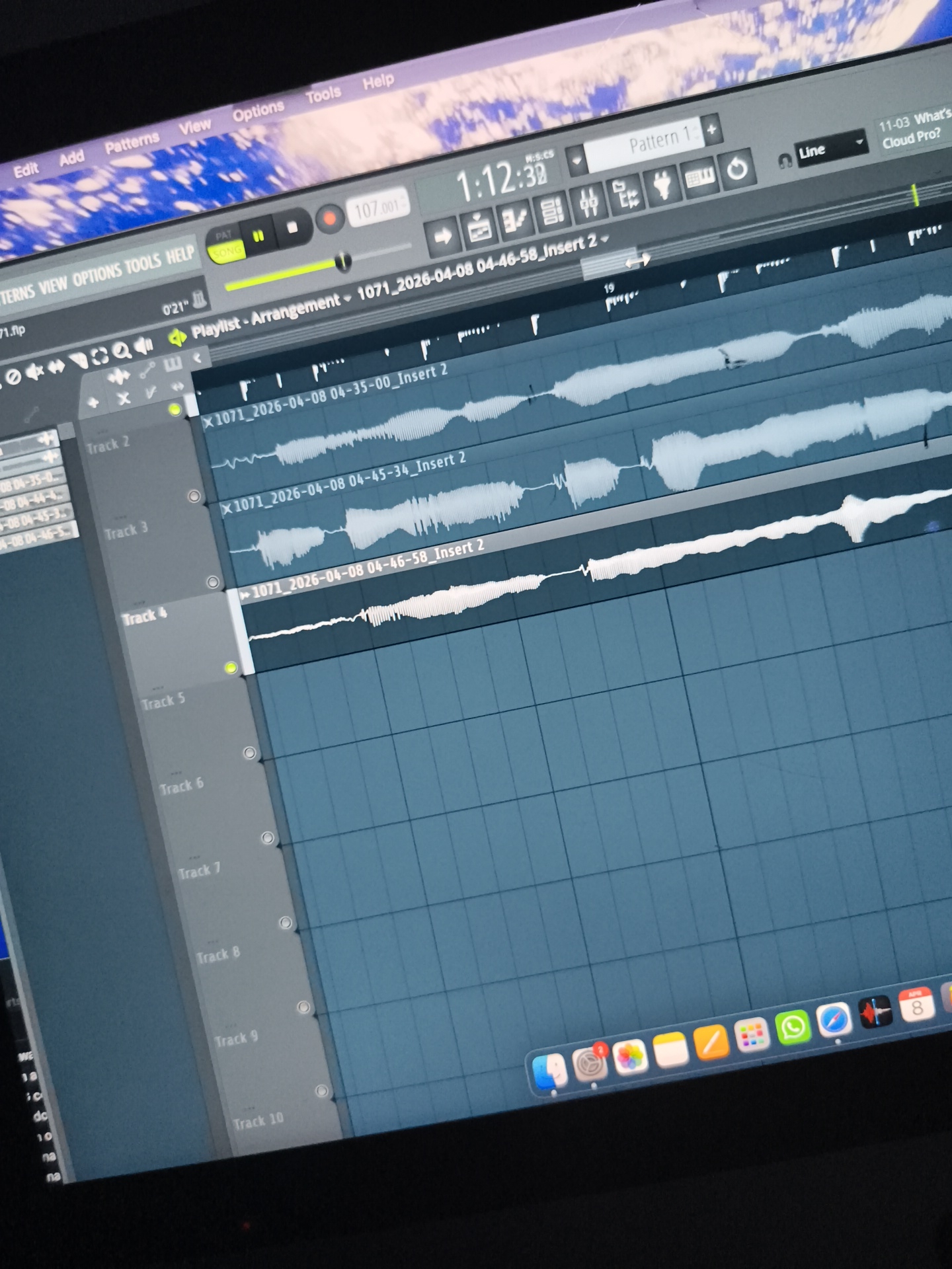 The image shows a computer screen displaying the FL Studio digital audio workstation software. The program appears to be in the "Playlist" view, with several audio tracks loaded and waveforms visible. The tracks are labeled with file names that include date and time stamps (e.g., "1071_2026-04-08 04-46-58_Insert 2"). Track 4 is highlighted, suggesting it is the active track.
The top of the screen displays the FL Studio menu bar (Edit, Add, Patterns, View, Options, Tools, Help) and a transport control panel with tempo set to 107.001 BPM and a timer reading 1:12:39.
The bottom of the screen shows the macOS dock with various application icons, including Finder, Settings, Mail, Safari, WhatsApp, and a calendar icon indicating August 8th.
The background behind the screen is blurred but appears to be an image of the earth from space.
There is no information in the image to suggest that this scene is located in Diepholz, Germany.