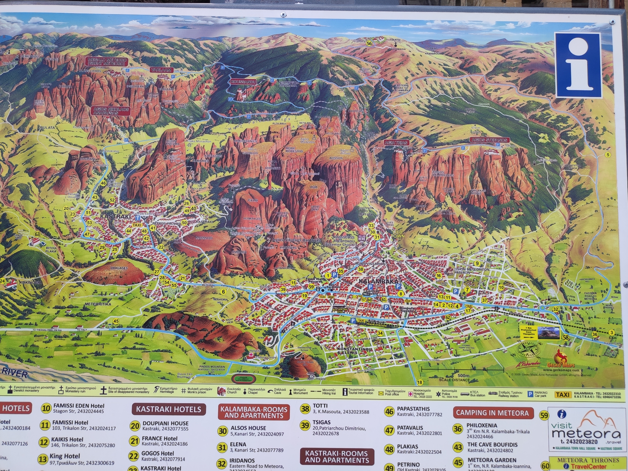 This is a detailed, illustrated tourist map of Meteora, Greece, a region famous for its rock formations and ancient monasteries. The map depicts the iconic sandstone pillars with monasteries perched atop them, including Megalo Meteoro and Roussanou. The town of Kalabaka is shown in the lower right, with Kastraki nestled closer to the rocks.
Various points of interest are clearly labeled in both Greek and English, such as "Derelict monastery," "Hermitage," "Monk's prison," and "Cave." Hotels, restaurants, and apartments are listed with their respective names and contact numbers. Transportation information is also provided, including taxi services, bus stations, and a railway station. Roads and footpaths are marked, indicating walking routes to the monasteries.
The map shows a clear, sunny day, with the landscape illuminated by daylight. The terrain is mountainous and rugged, characterized by the distinctive rocky pinnacles. The overall impression is one of a popular tourist destination, with an emphasis on cultural and natural attractions. The map includes a scale bar, a compass rose, and copyright information.